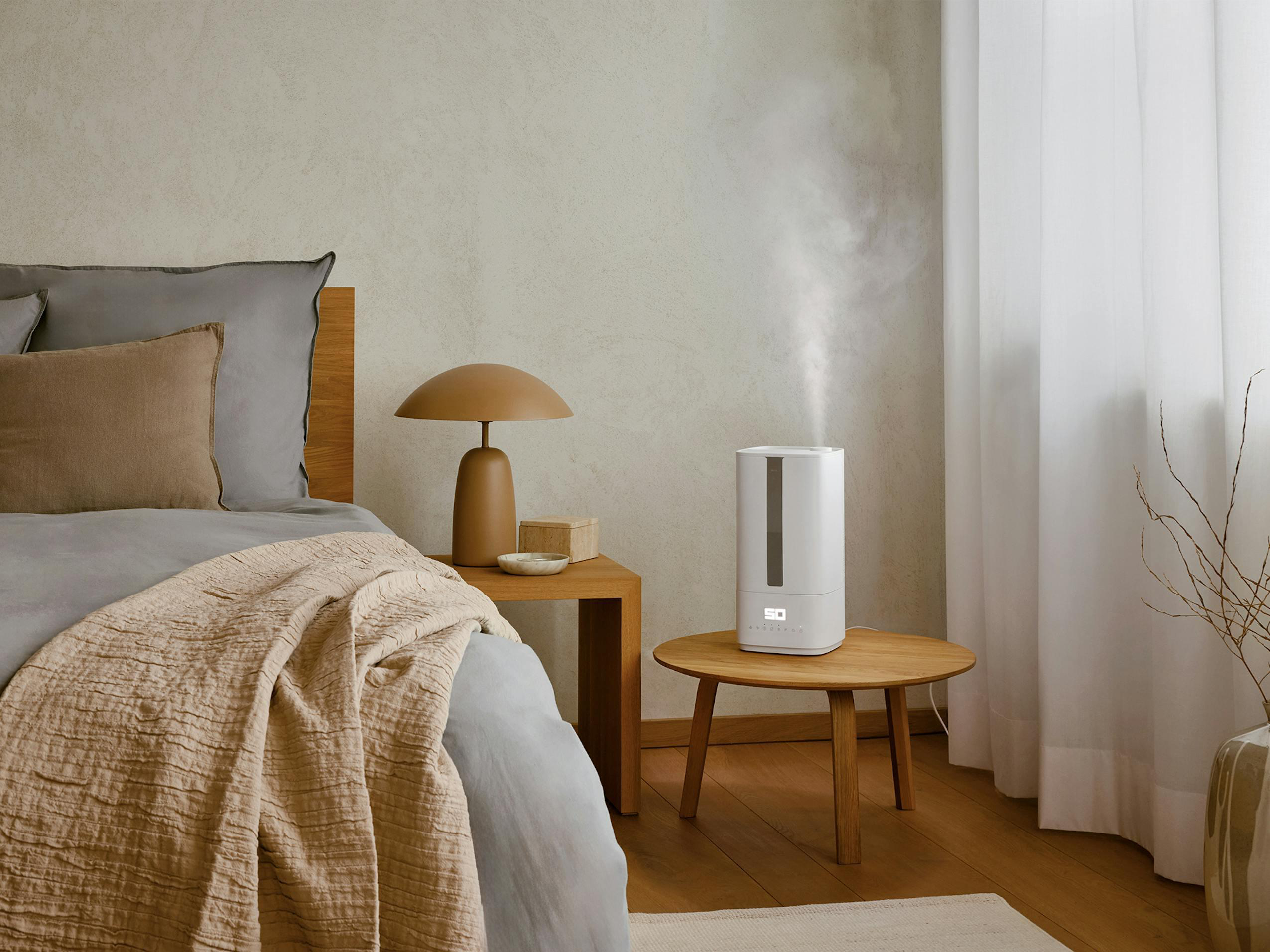 Schlafzimmer mit Bett, Nachttischen, Luftbefeuchter und Fenster. Neutrale Farben dominieren.