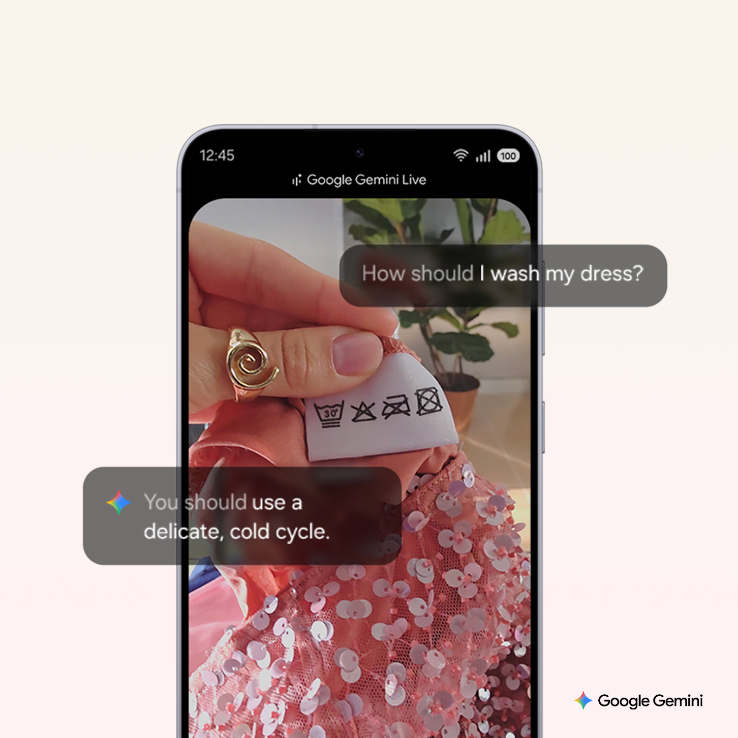 Una pantalla de teléfono muestra una etiqueta de vestido con instrucciones de lavado. Una mano sostiene la etiqueta. Gemini sugiere un ciclo frío y delicado.