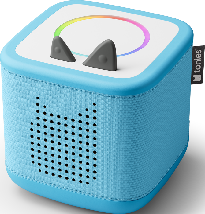 Une Toniebox bleue. C'est un cube avec un haut-parleur, des boutons en forme d'oreilles de chat et un anneau lumineux coloré.
