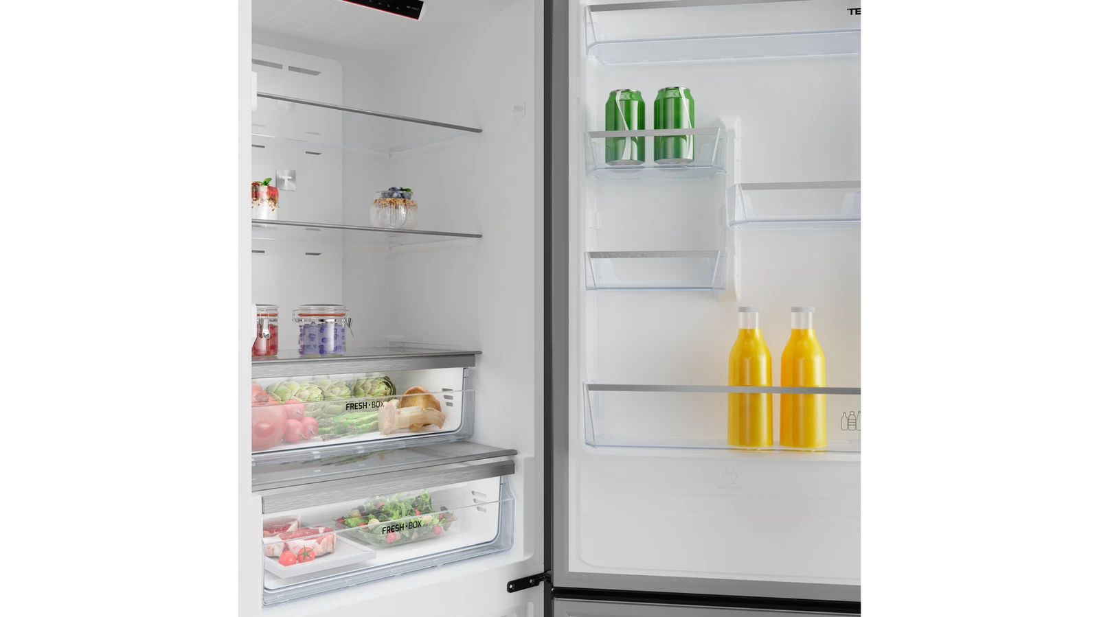 Refrigerador abierto lleno de comida y bebidas. Dos latas, dos botellas de jugo, estantes de vidrio y productos frescos en cajones.