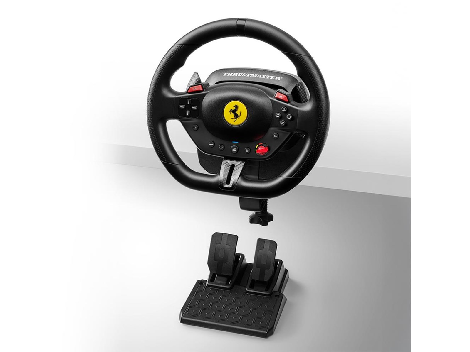 Un volante negro de Ferrari con pedales. Está sobre un fondo blanco.