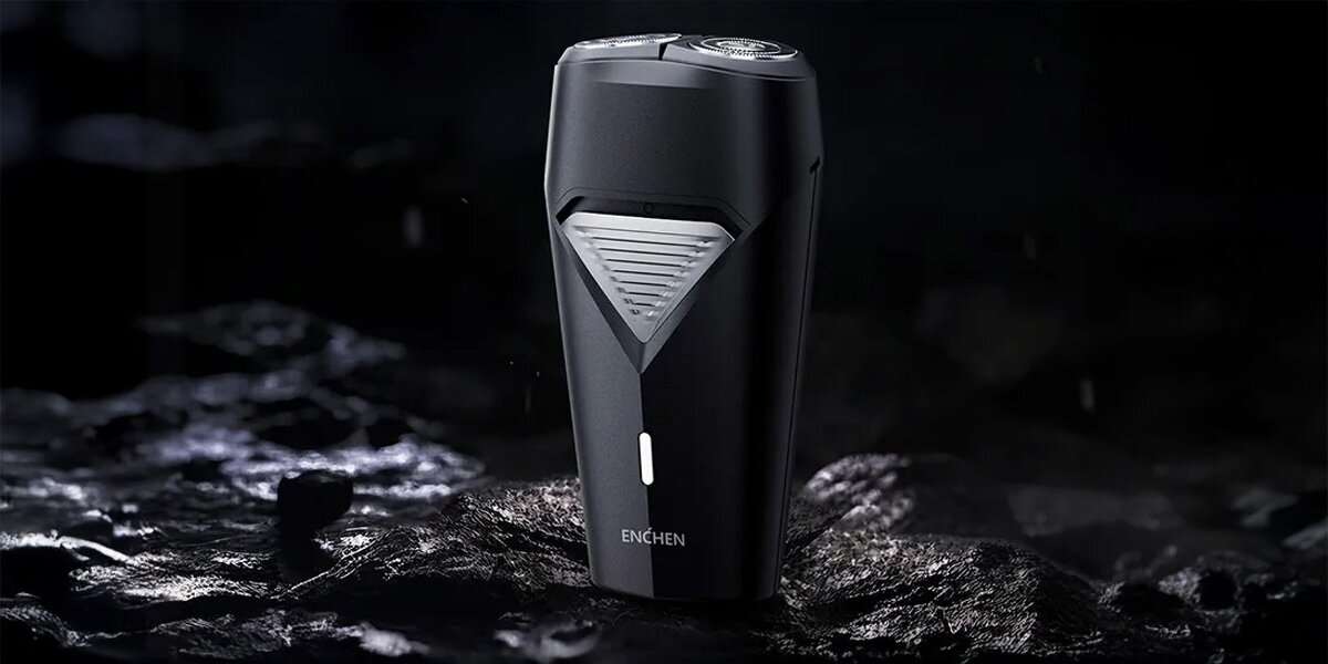 Czarna golarka elektryczna stoi na ciemnej, teksturowanej powierzchni. Ma trójkątny design i widoczna jest marka 'ENCHEN'.