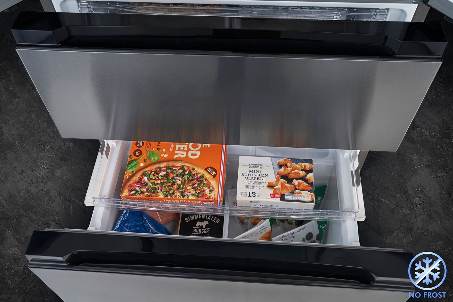 Un cassetto del frigorifero è aperto, rivelando cibo surgelato. Pizza, croissant, hamburger e altri articoli sono visibili.