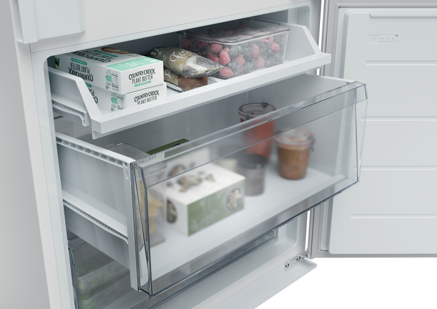 Interior de refrigerador con mantequilla vegetal, bayas y frascos. Los cajones están abiertos, mostrando el contenido. Interior blanco.
