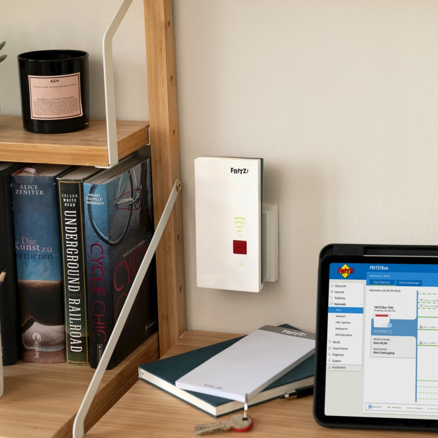 Un router e un tablet sono su una scrivania con libri e una candela. Il tablet mostra una pagina di impostazioni di rete.