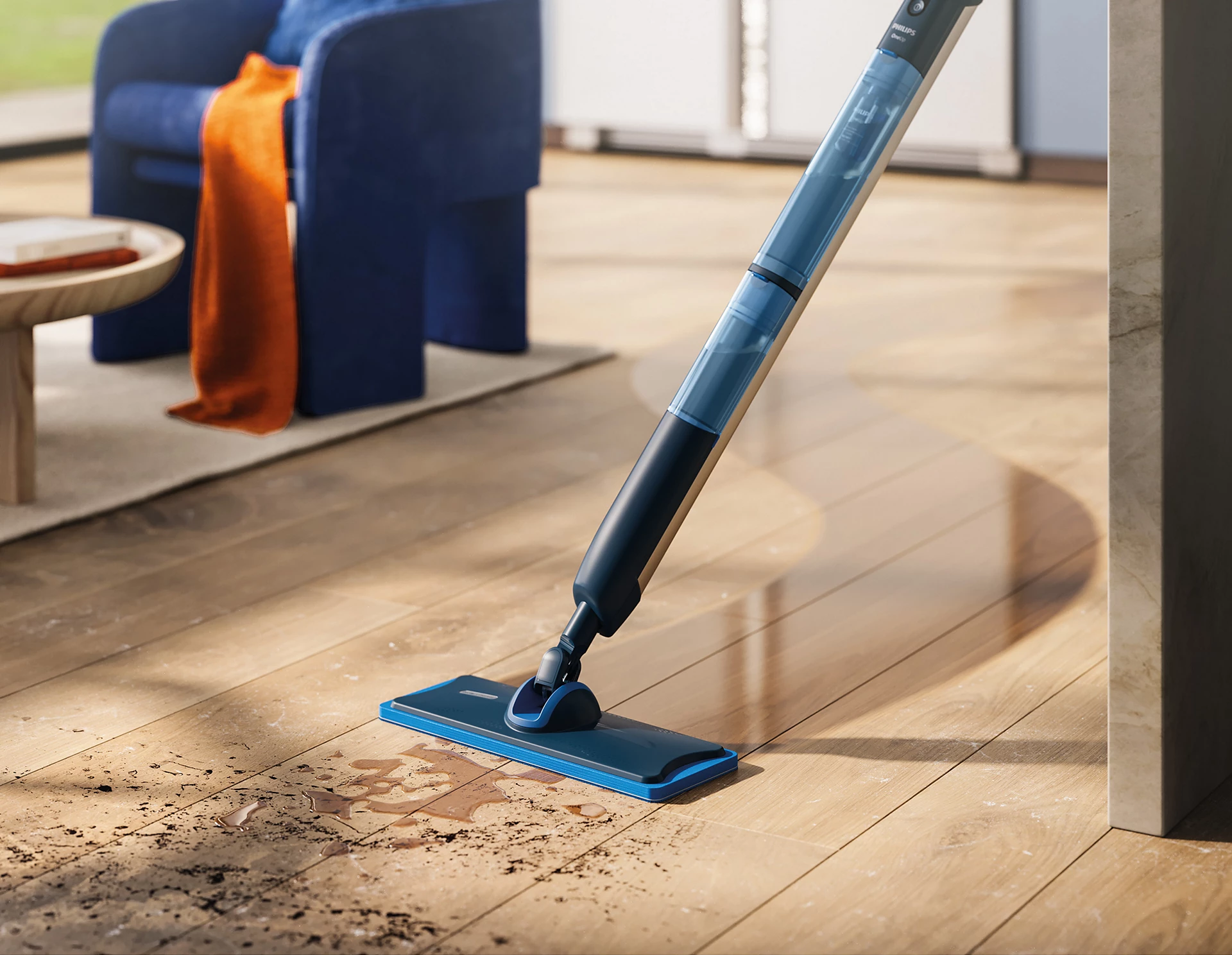 Une serpillère bleue et noire nettoie un plancher en bois avec de la saleté et de l'eau. Un fauteuil bleu et une couverture orange sont en arrière-plan.