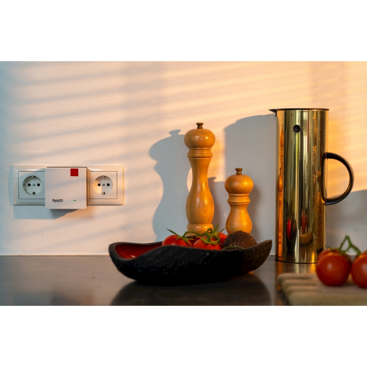 Una scena di cucina con pomodori, saliere e pepiere, una brocca dorata e una presa di corrente con un dispositivo Frit!.