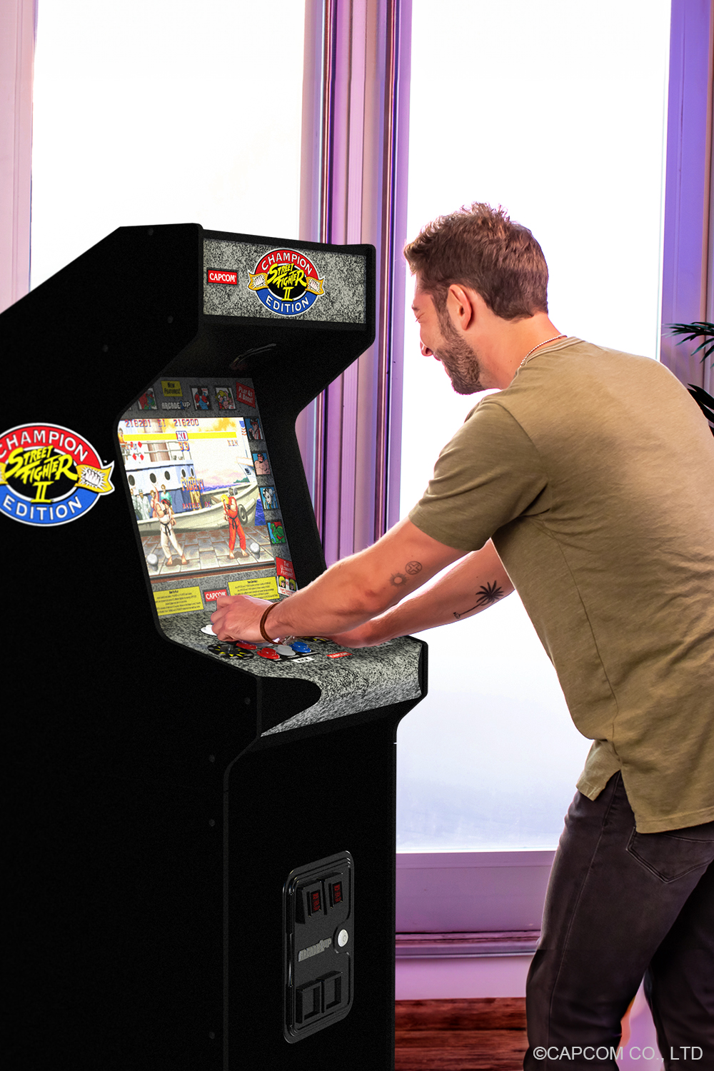 Férfi Street Fighter II arcade játékot játszik. Egy zöld pólós férfi játszik a játékkal. A játék képernyője látható. Világos ablak a háttérben.