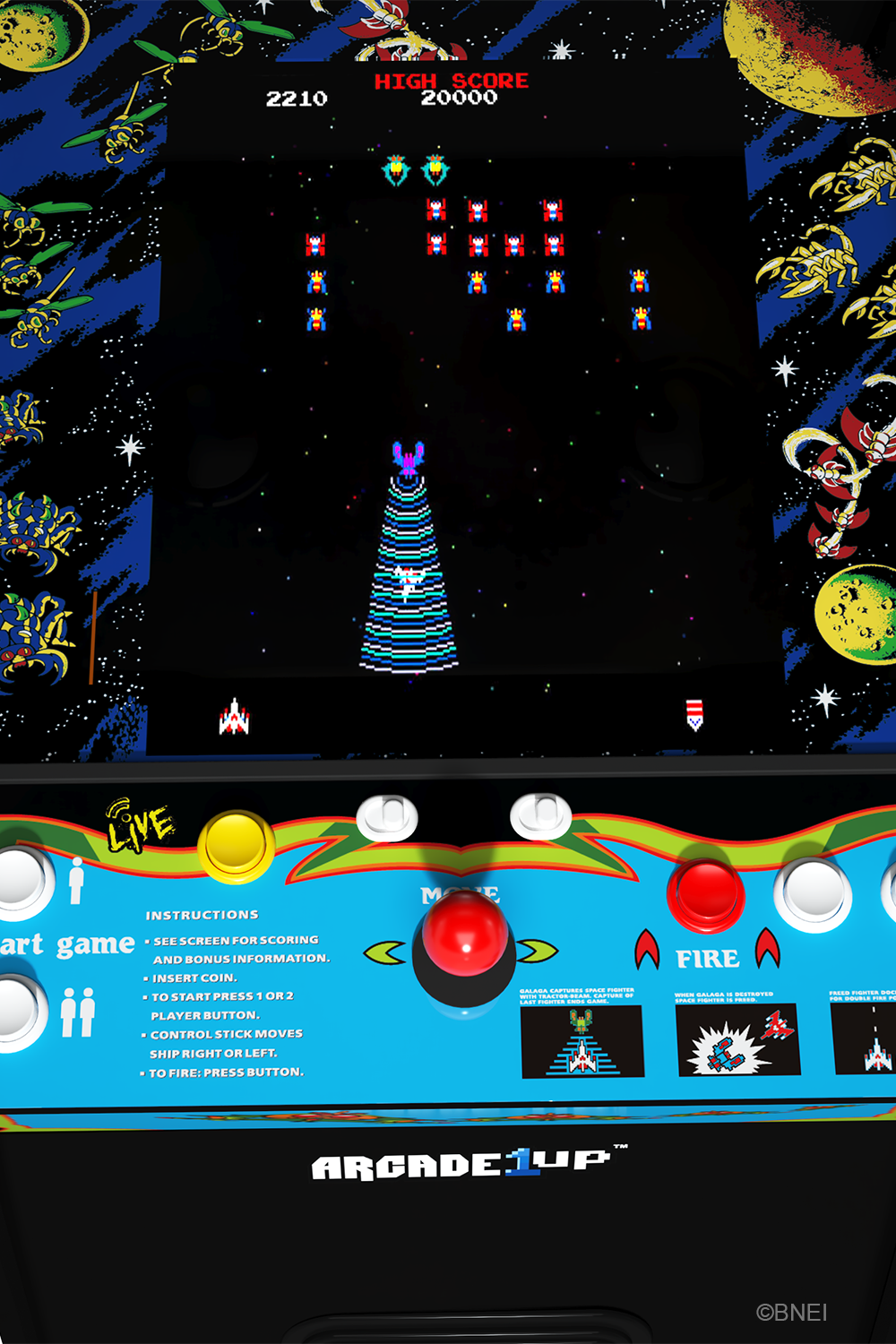 Egy arcade játék képernyője űrcsatát mutat. Az ellenséges hajók megtámadnak egy bázist. A vezérlőpanel gombokat és utasításokat tartalmaz.