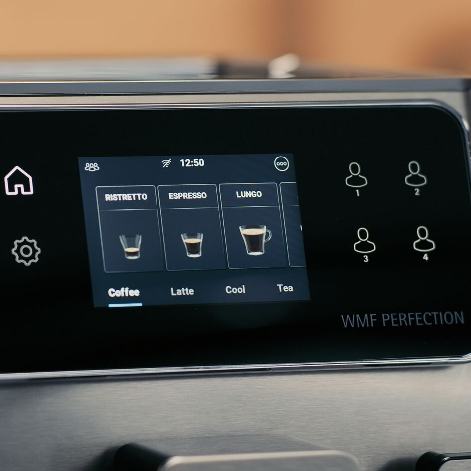 Una interfaz de máquina de café muestra opciones: Ristretto, Espresso, Lungo, Café, Latte, Cool y Té. La hora es 12:50.
