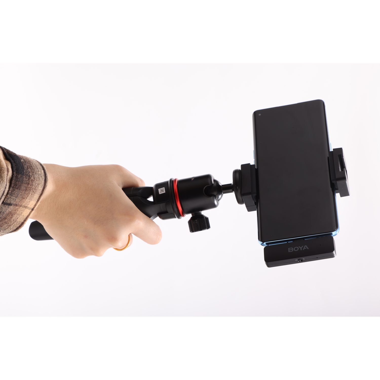 Hand holding a phone mounted on a tripod. The phone is black with a blue outline. The tripod is black and red.