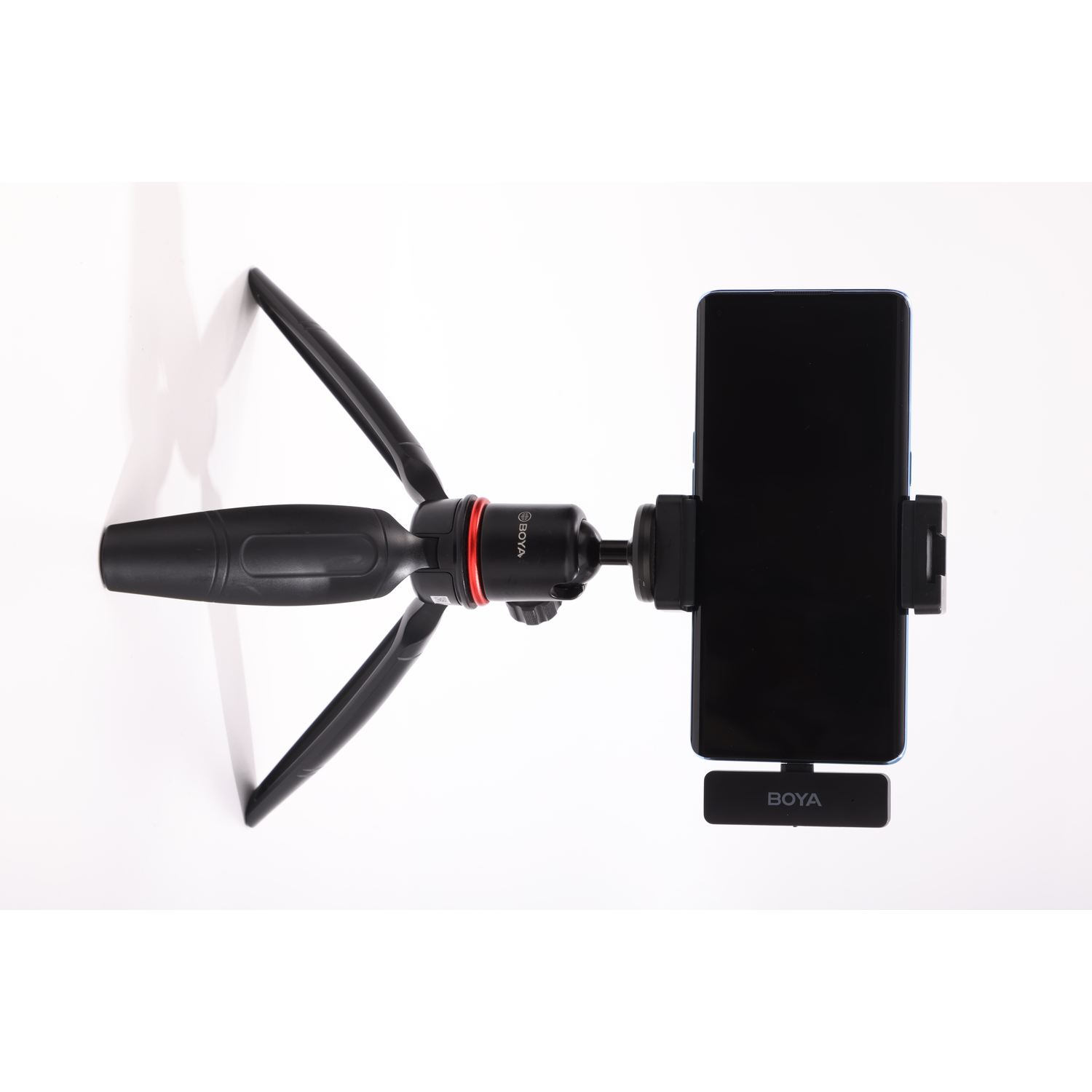 A black phone is mounted on a tripod. The tripod has black legs and a red ring. The background is white.