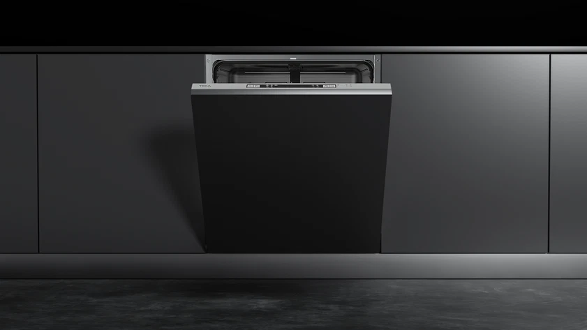 Un lavavajillas negro está abierto, integrado en armarios oscuros. La marca Teka es visible. La escena es interior.