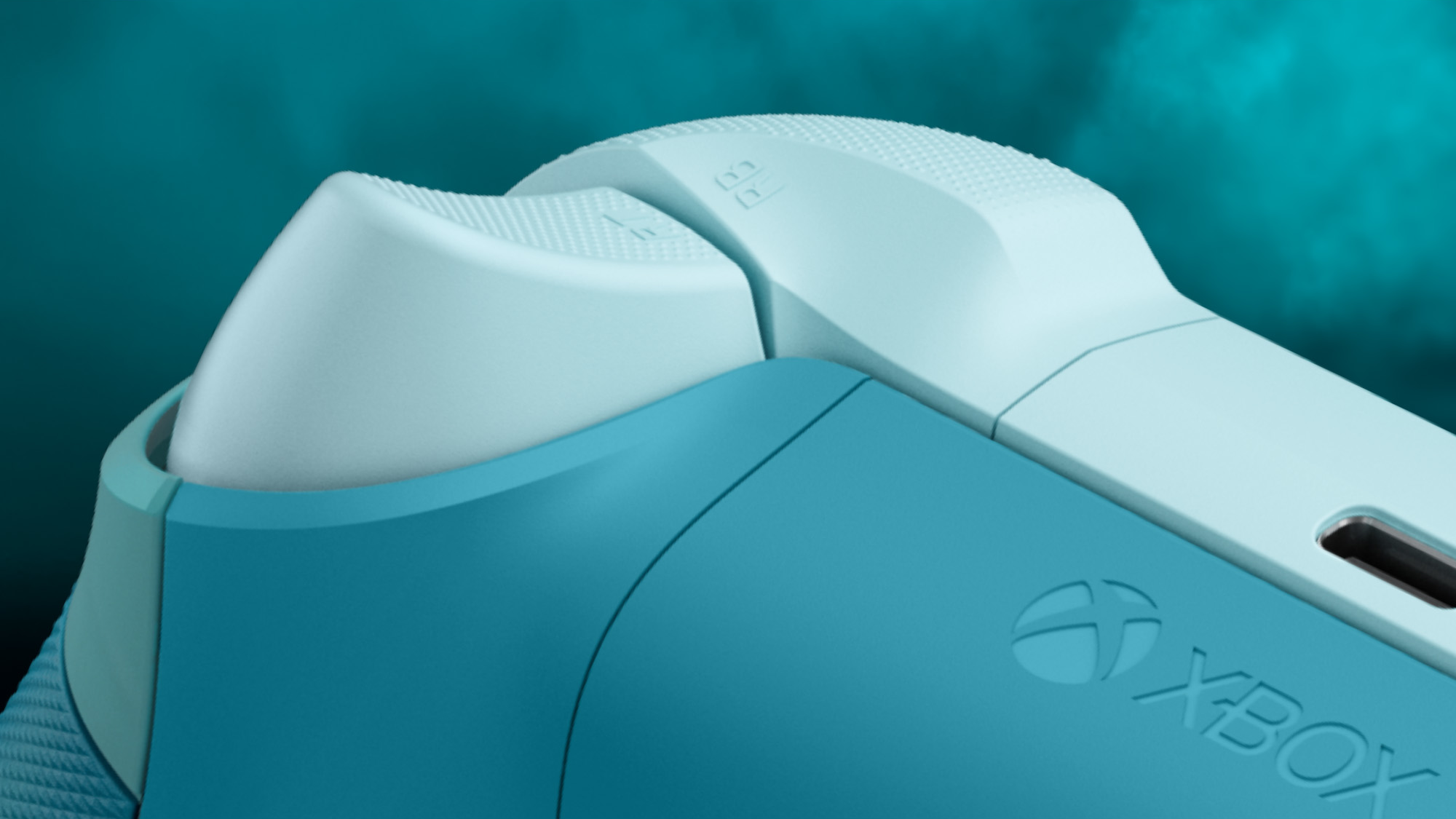 Nahaufnahme eines Xbox-Controllers in Türkis und Hellblau. Das Xbox-Logo ist sichtbar. Der Hintergrund ist türkis.