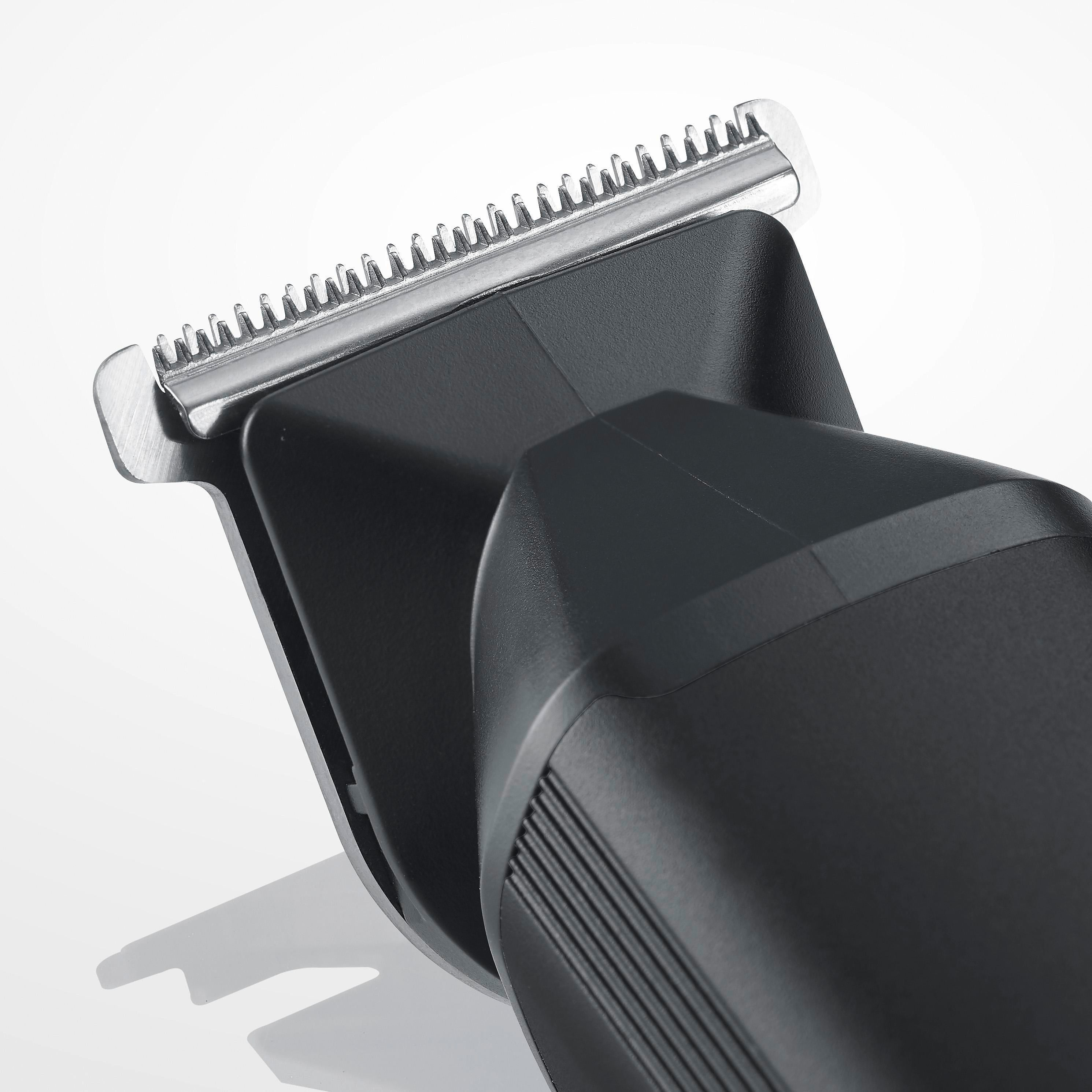 Zbliżenie czarnej golarki elektrycznej na białym tle. Ostrze jest srebrne, a korpus czarny.