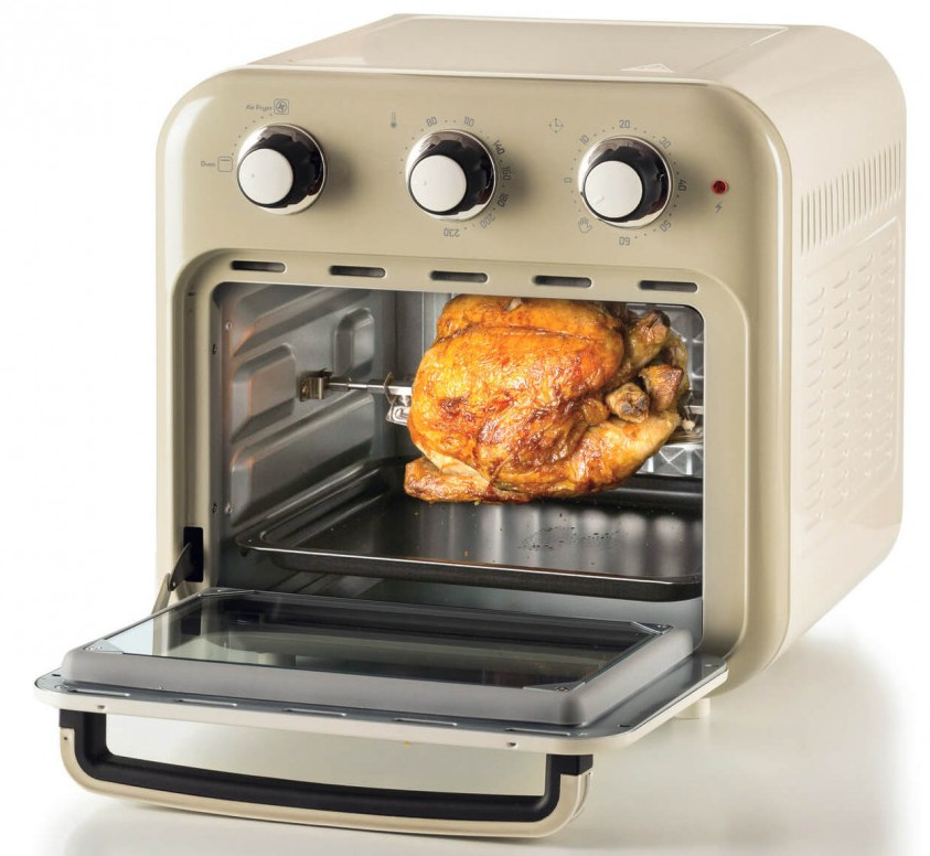 Otwarta beżowa frytkownica powietrzna z pieczonym kurczakiem w środku. Pokrętła na górze. Drzwi są otwarte.