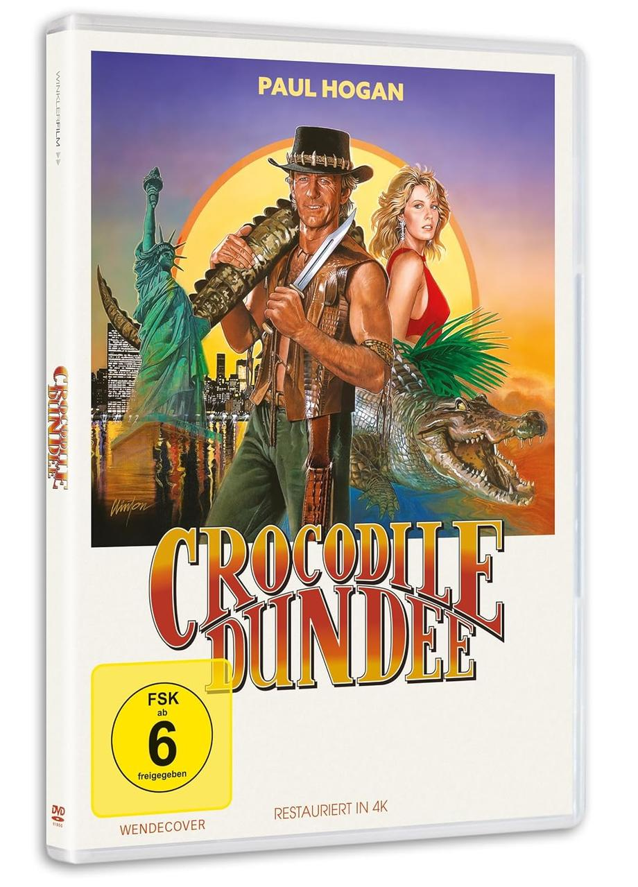 DVD-Cover von Crocodile Dundee. Mit Paul Hogan mit Messer und Alligator. Eine Frau in Rot, Freiheitsstatue und Titel.