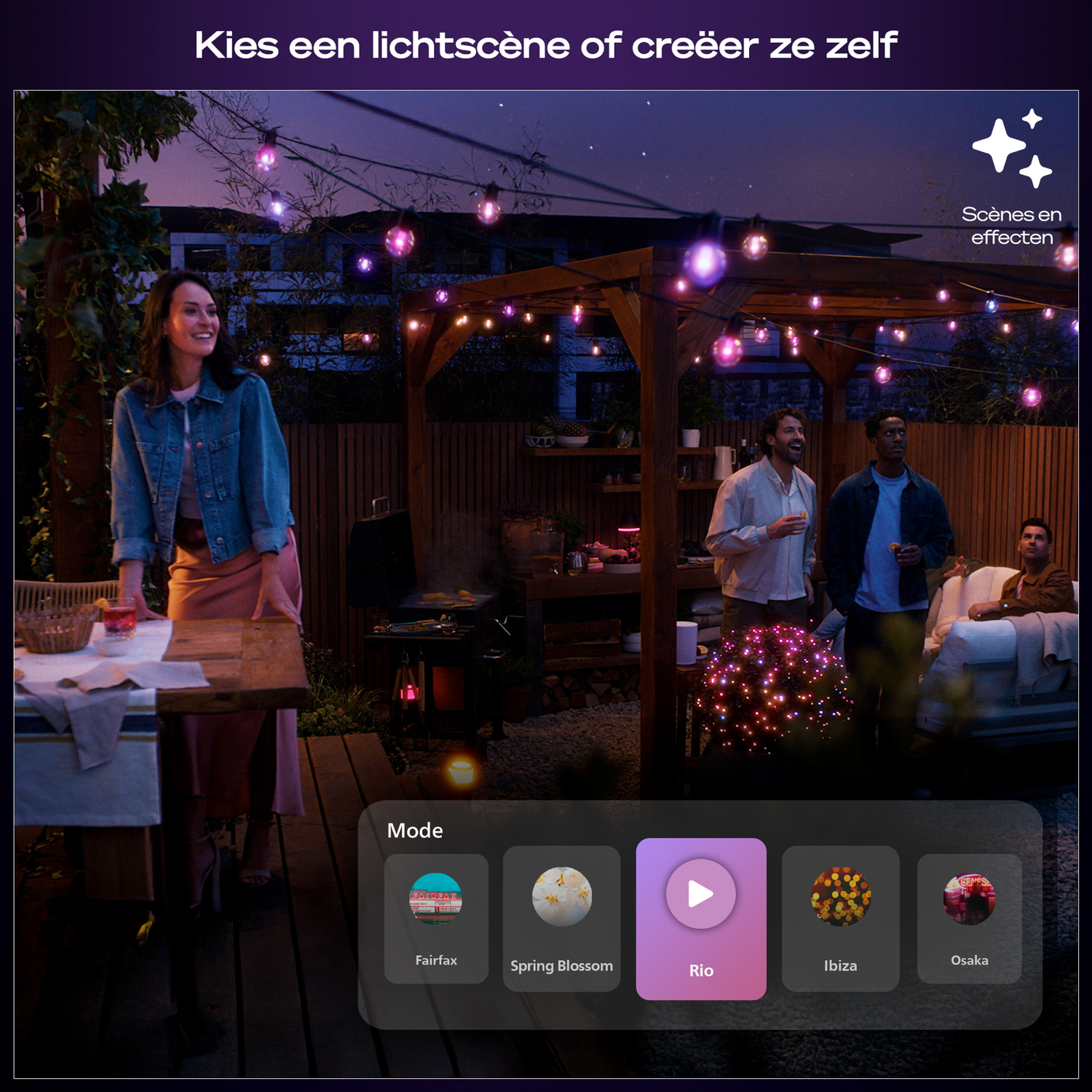 A group of people at a night gathering with string lights. A woman stands by a table, others converse and relax.