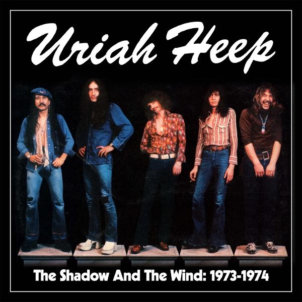 Uriah Heep-Bandmitglieder posieren vor schwarzem Hintergrund. Der Text lautet: „The Shadow And The Wind: 1973-1974“.