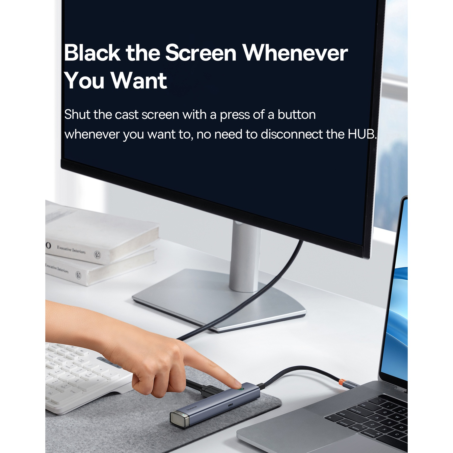 Una mano preme un pulsante su un hub collegato a un laptop e a un monitor. Il testo sullo schermo dice 'Black the Screen Whenever You Want'.
