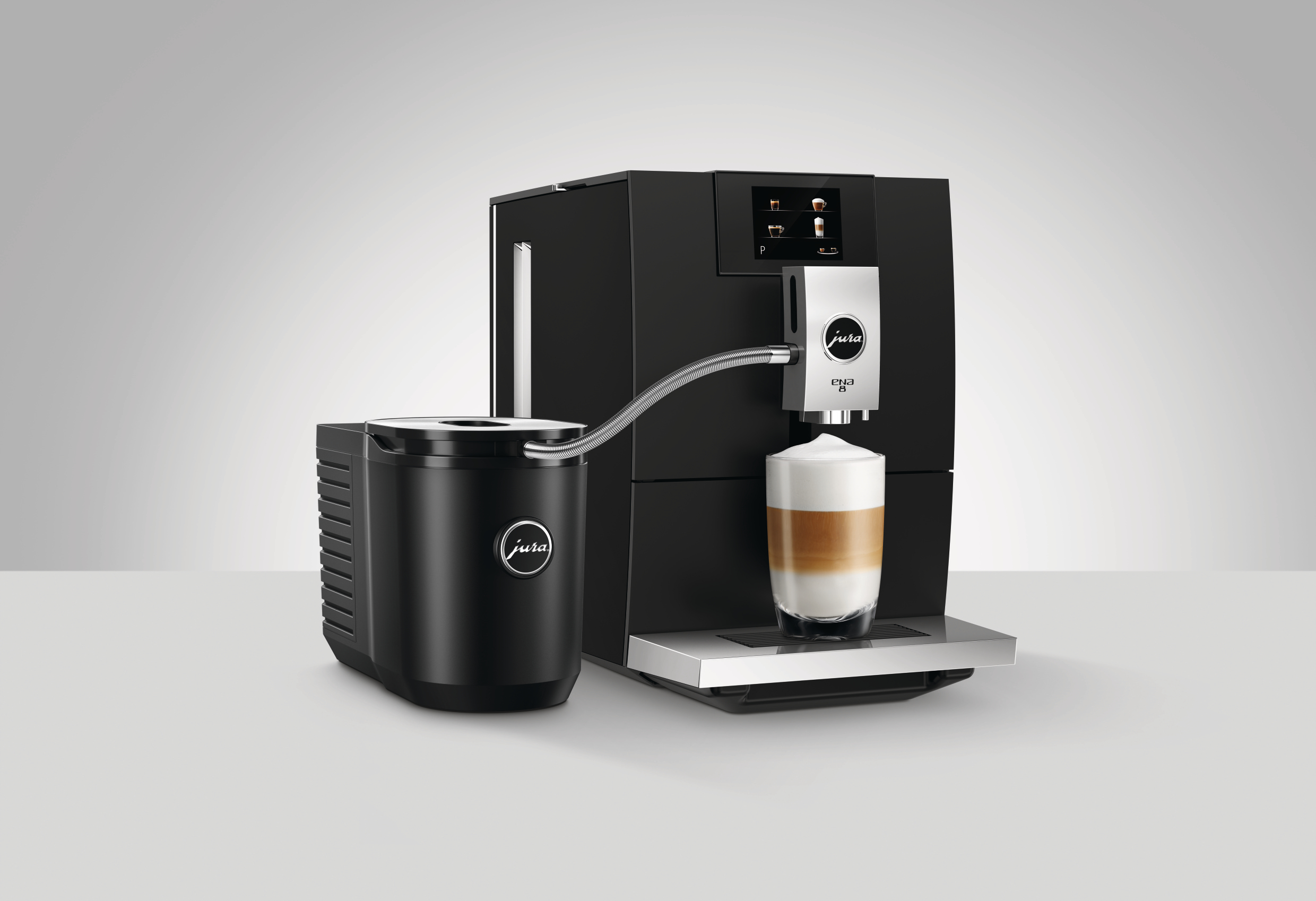 Schwarze Jura ENA 8 Kaffeemaschine mit Milchaufschäumer. Ein Glas geschichteten Latte Macchiato wird ausgegeben.