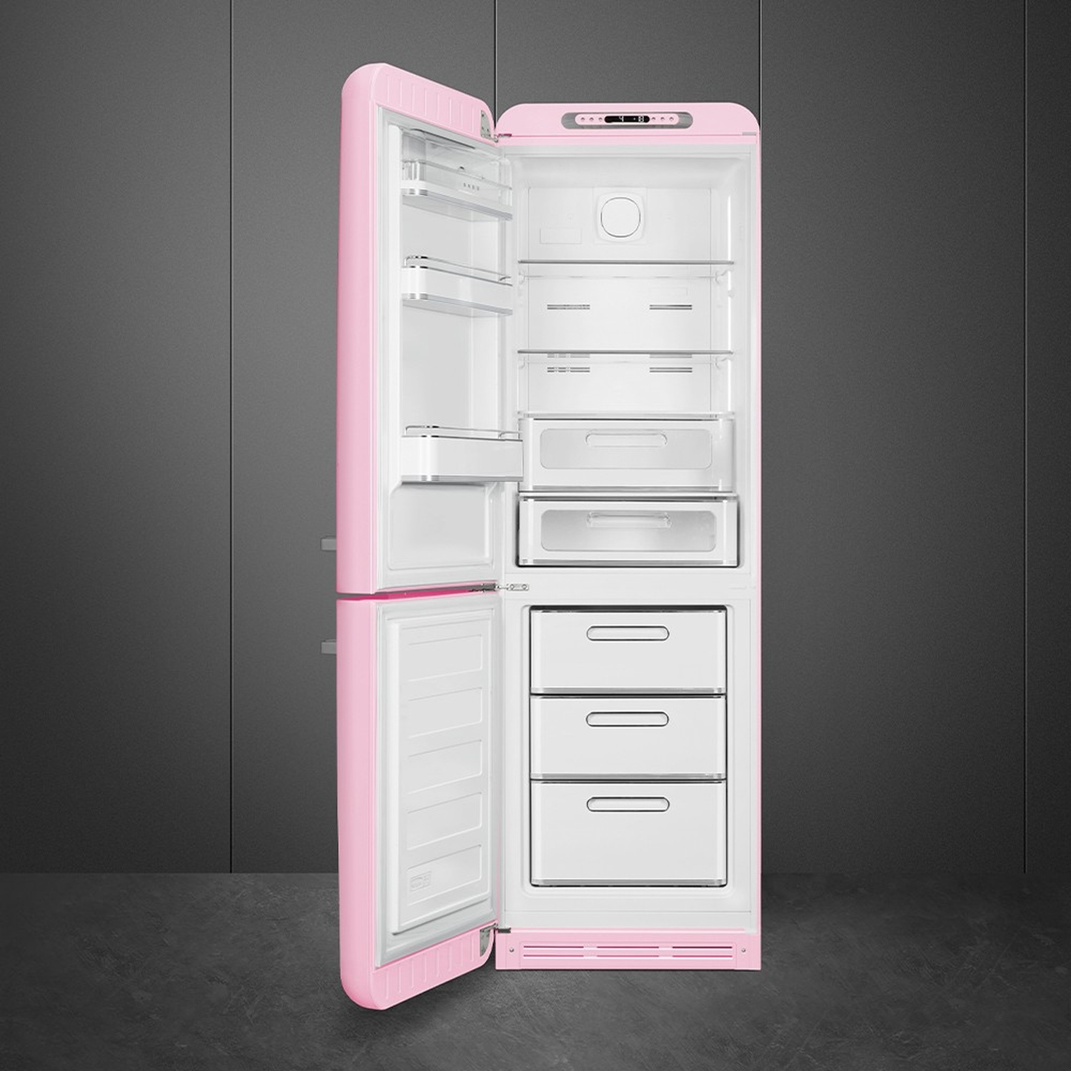 Un frigorifero rosa in stile retrò è aperto, rivelando ripiani e cassetti interni bianchi. Lo sfondo è una parete e un pavimento grigio scuro.