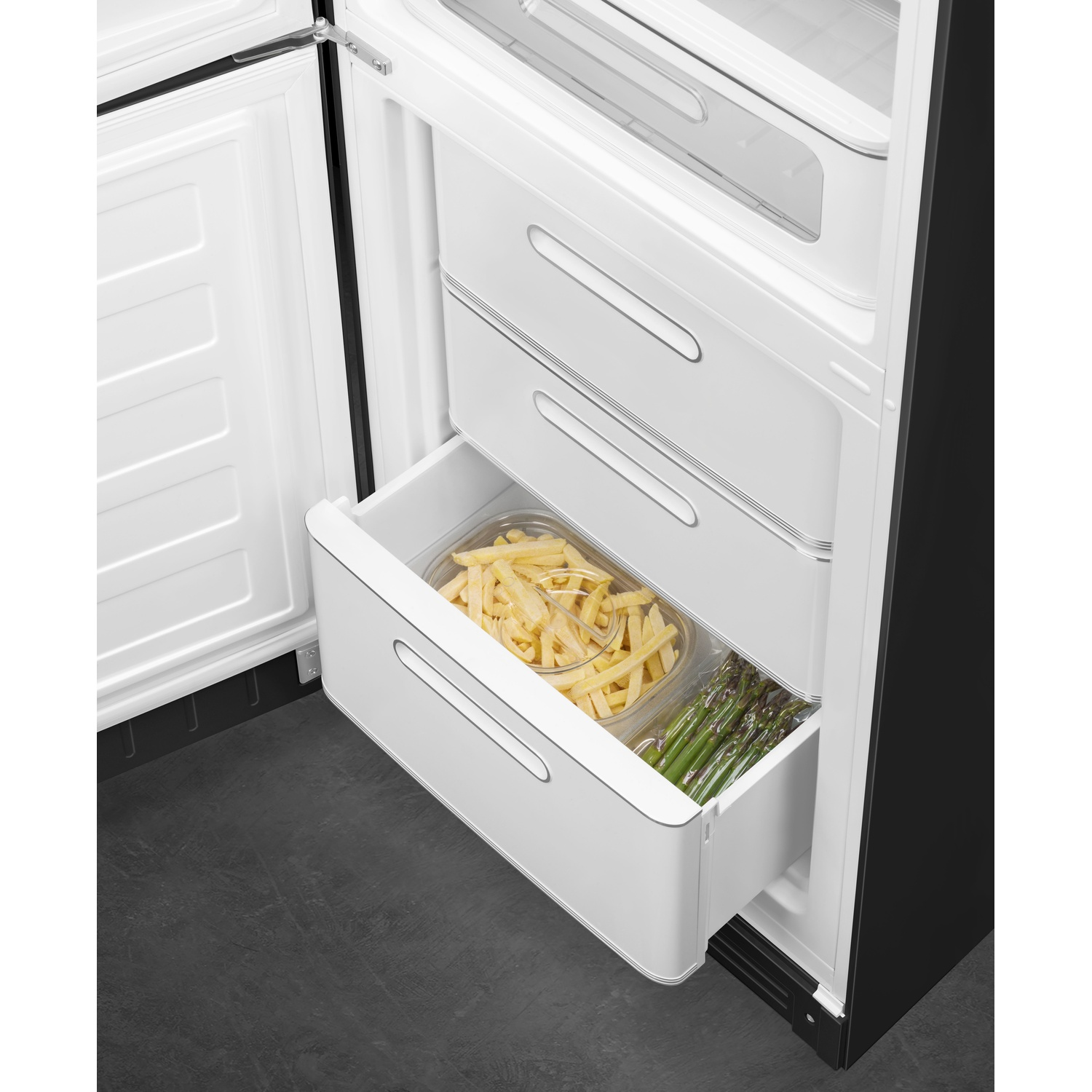 Frigorifero aperto con un cassetto contenente patatine fritte e asparagi. La porta è bianca, lo sfondo è scuro.