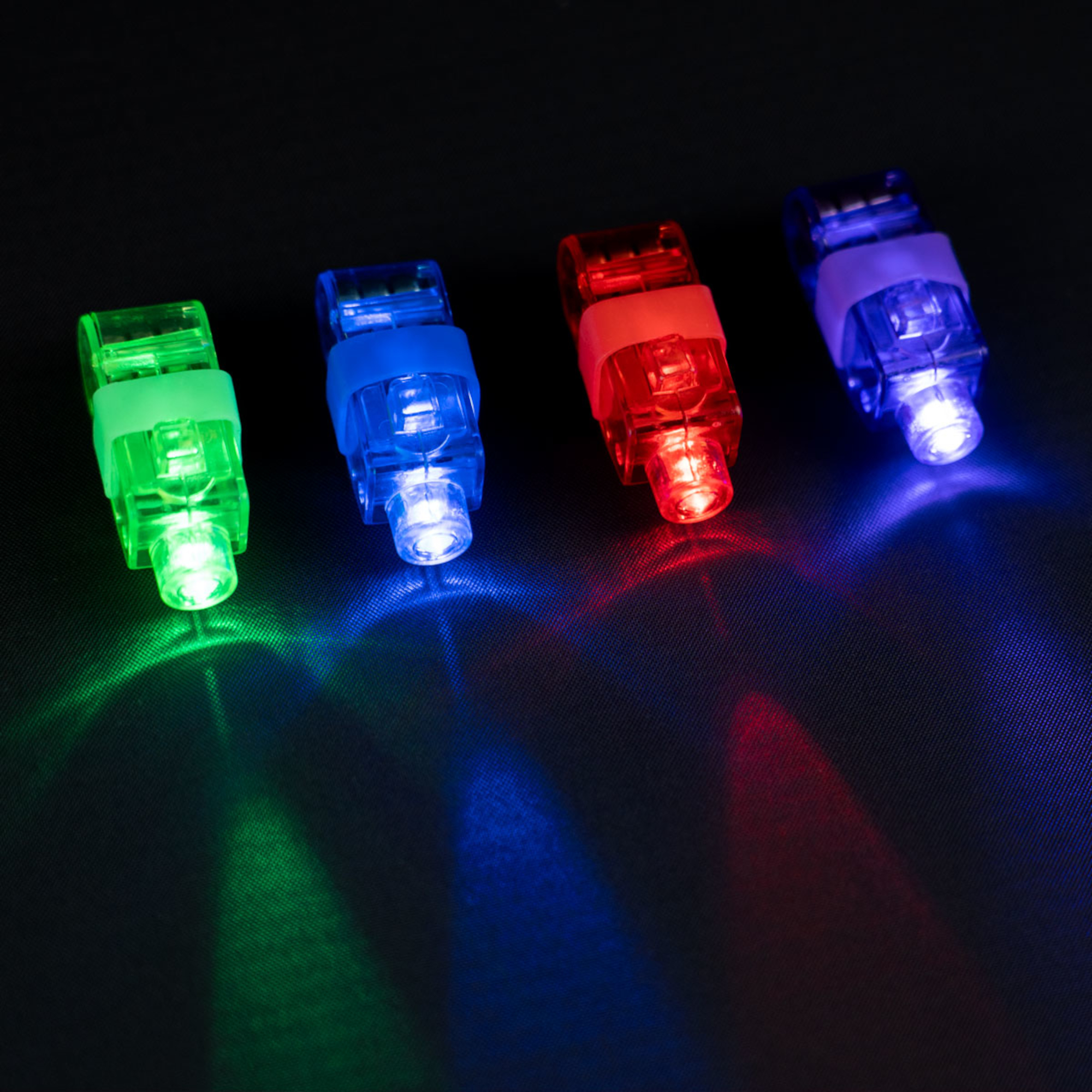 Vier Fingerlichter sind diagonal angeordnet. Sie leuchten grün, blau, rot und lila auf einer schwarzen strukturierten Oberfläche.