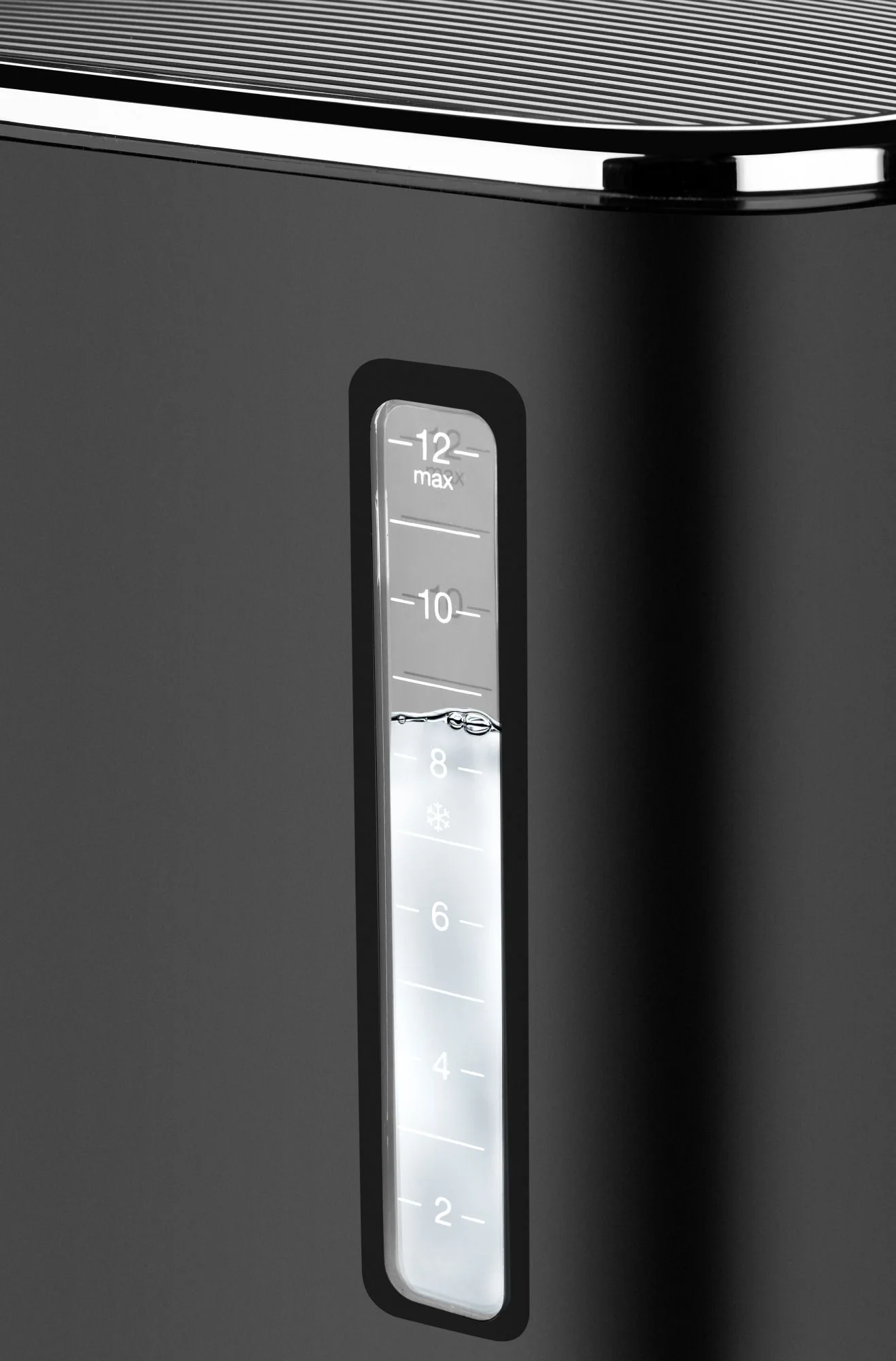 Czarny sprzęt ze wskaźnikiem poziomu wody. Poziom wody znajduje się pomiędzy 8 a 10. Urządzenie posiada linię maksymalnego napełnienia.