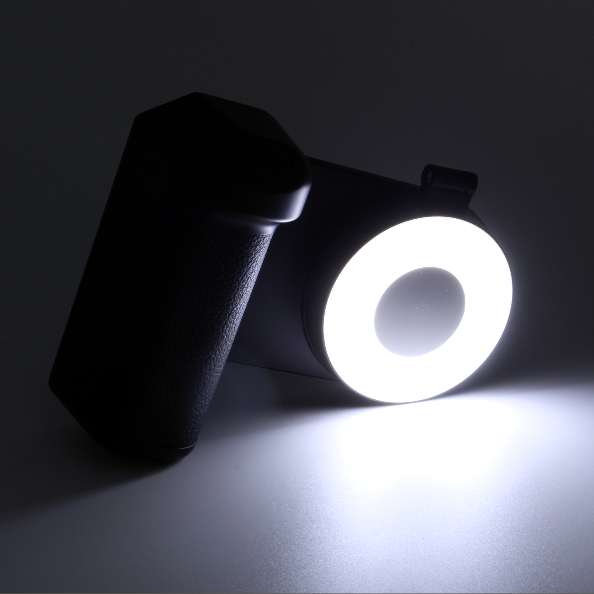 Eine schwarze Kamera mit einem hellweißen kreisförmigen Licht. Das Licht beleuchtet die Szene von der Linse der Kamera, mit dunklem Hintergrund.