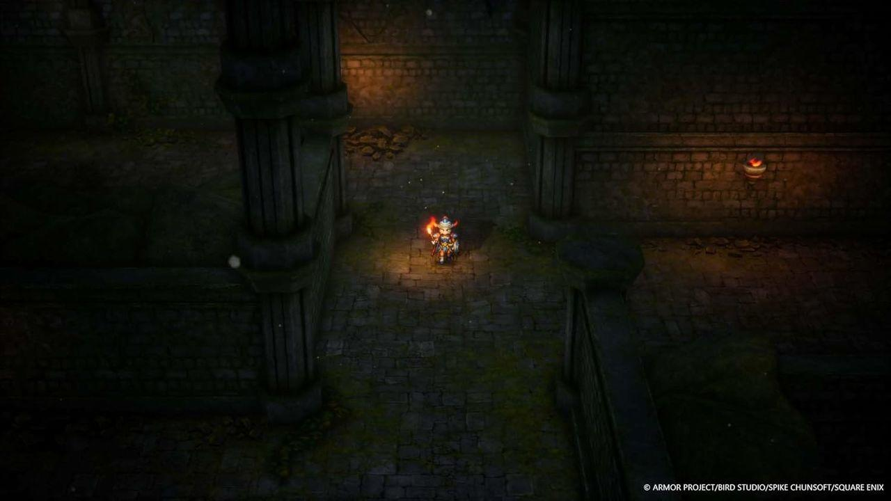 Ein Charakter mit einer Fackel geht einen Steinkorridor entlang. Dunkle Wände und Säulen säumen den Weg. In der Ferne leuchtet eine Leuchte.
