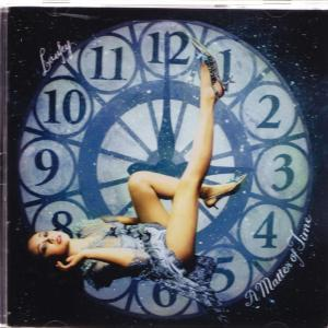Frau im Kleid, Beine hoch, auf Zifferblatt. Zahlen sichtbar. Titel "A Matter of Time".