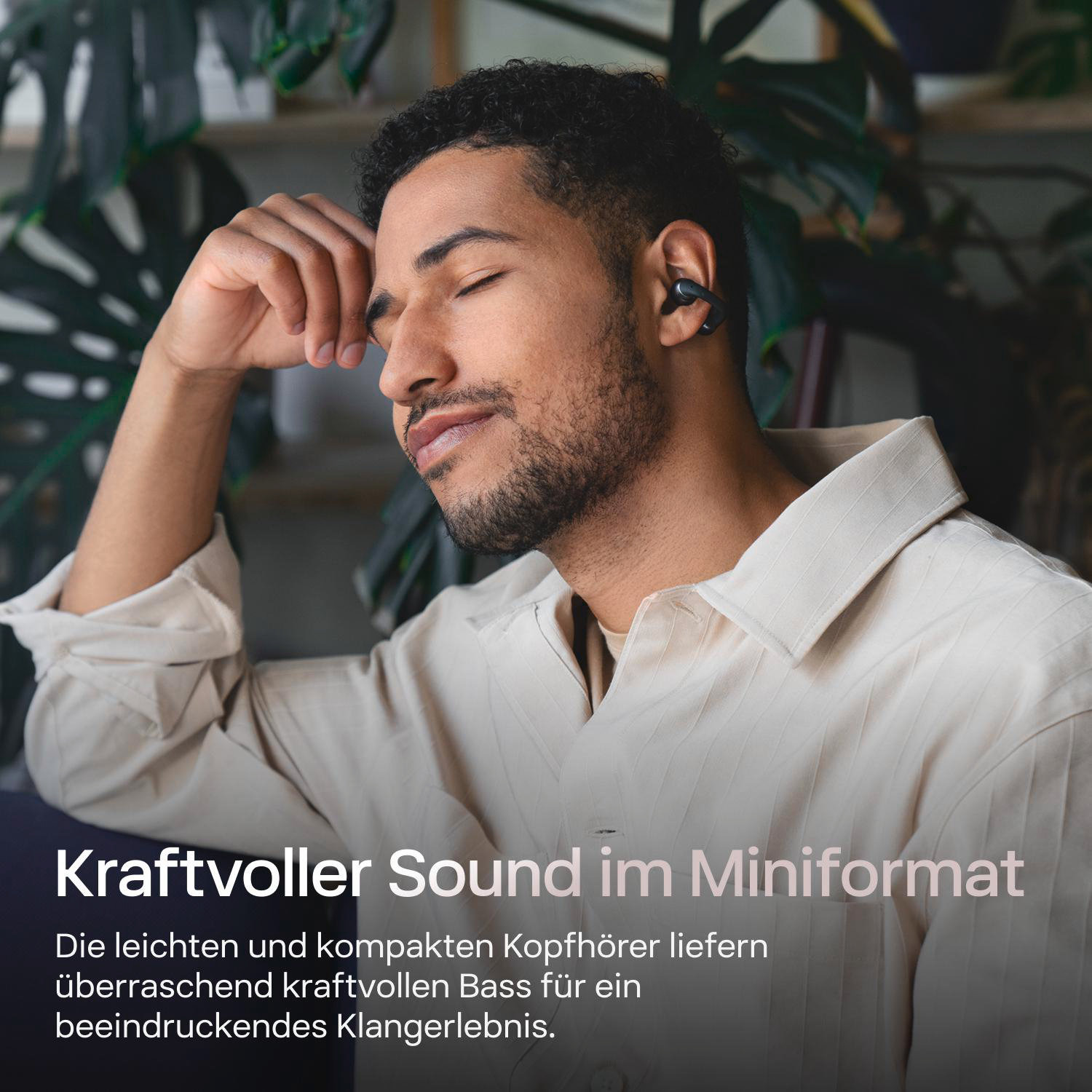 Ein Mann mit geschlossenen Augen trägt Ohrhörer. Er stützt seinen Kopf auf seine Hand. Text unten: Kraftvoller Sound im Mini-Format.