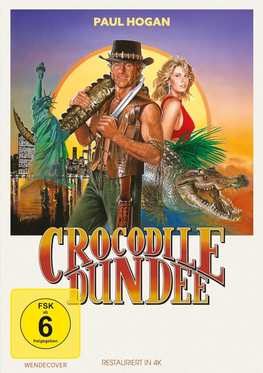 Filmplakat für Crocodile Dundee. Paul Hogan hält ein Messer und ein Krokodil. Freiheitsstatue und eine Frau in Rot. Titel unten.
