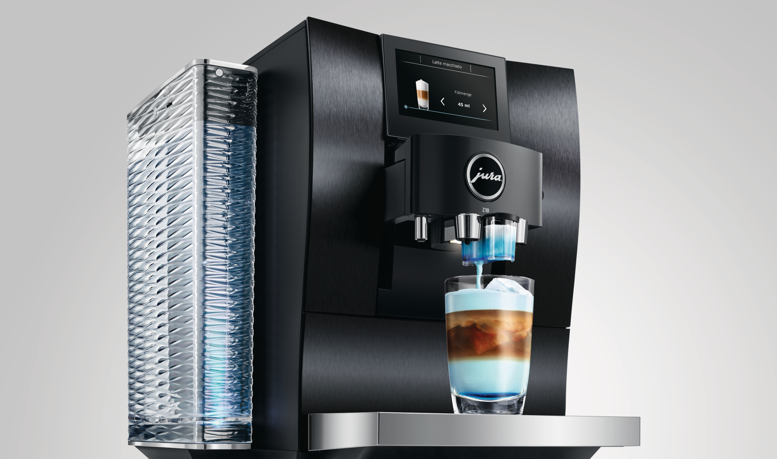 Eine schwarze Jura Z10 Kaffeemaschine, die einen Latte Macchiato zubereitet. Milch- und Kaffeeschichten sind im Glas sichtbar.