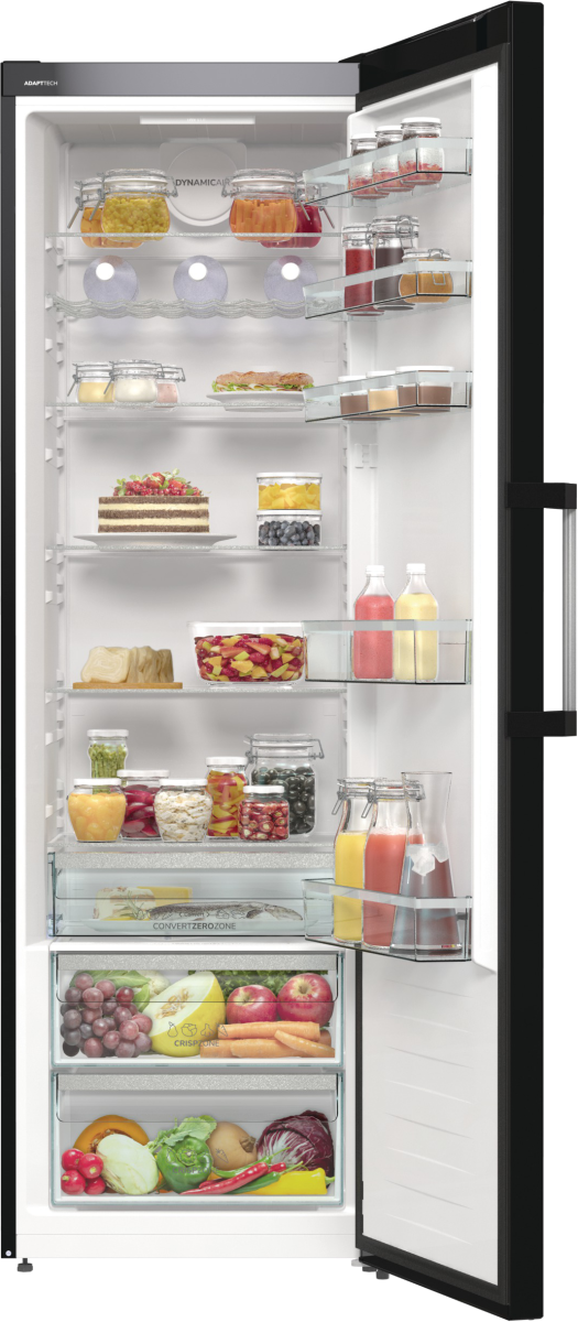 Otwarta lodówka wypełniona jedzeniem. Widoczne są słoiki, butelki, owoce i warzywa. Drzwi są otwarte.