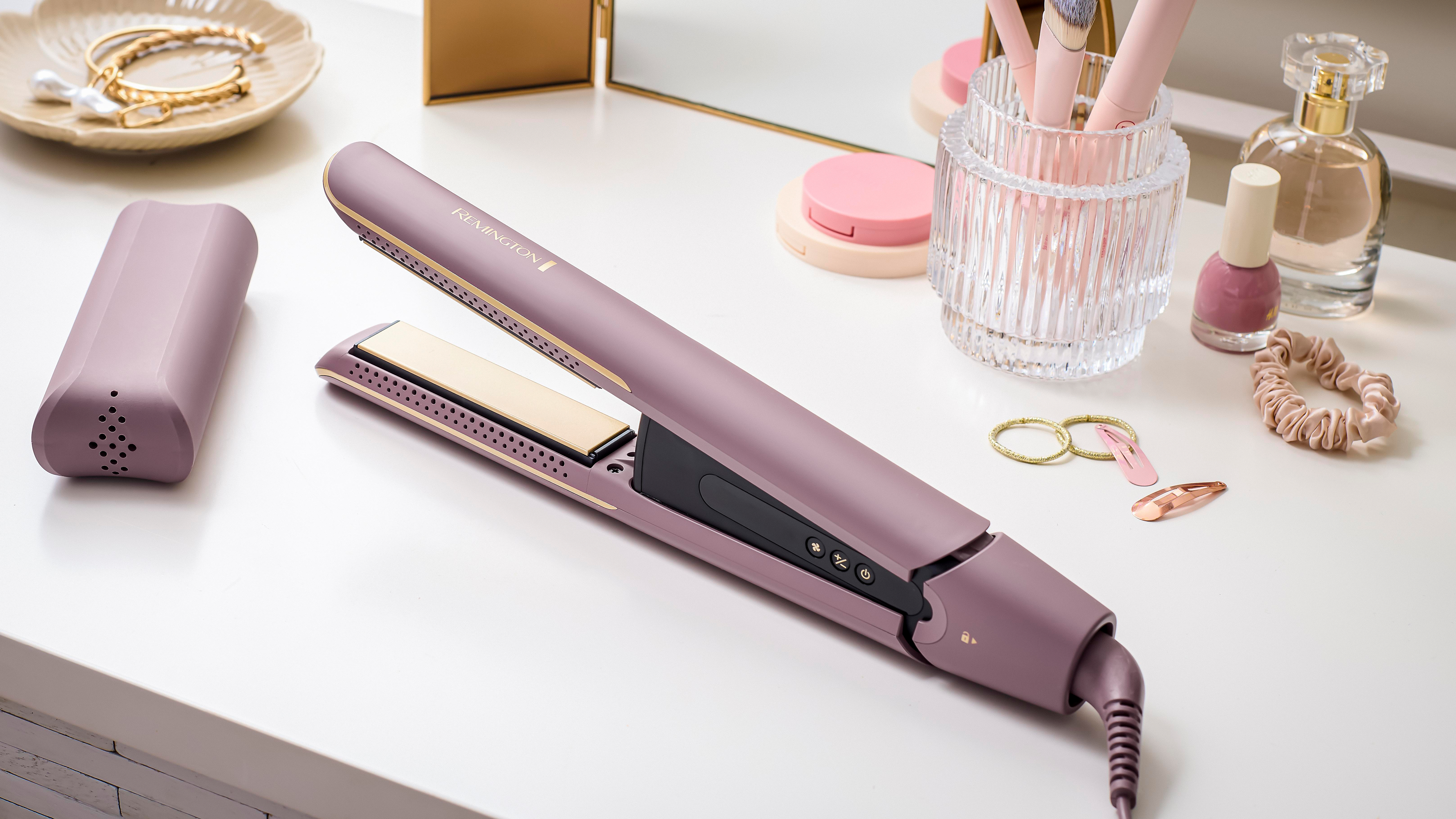Ein Glätteisen mit Zubehör auf weißer Oberfläche. Enthält Haarglätter, Schmuck, Make-up und Haarschmuck.
