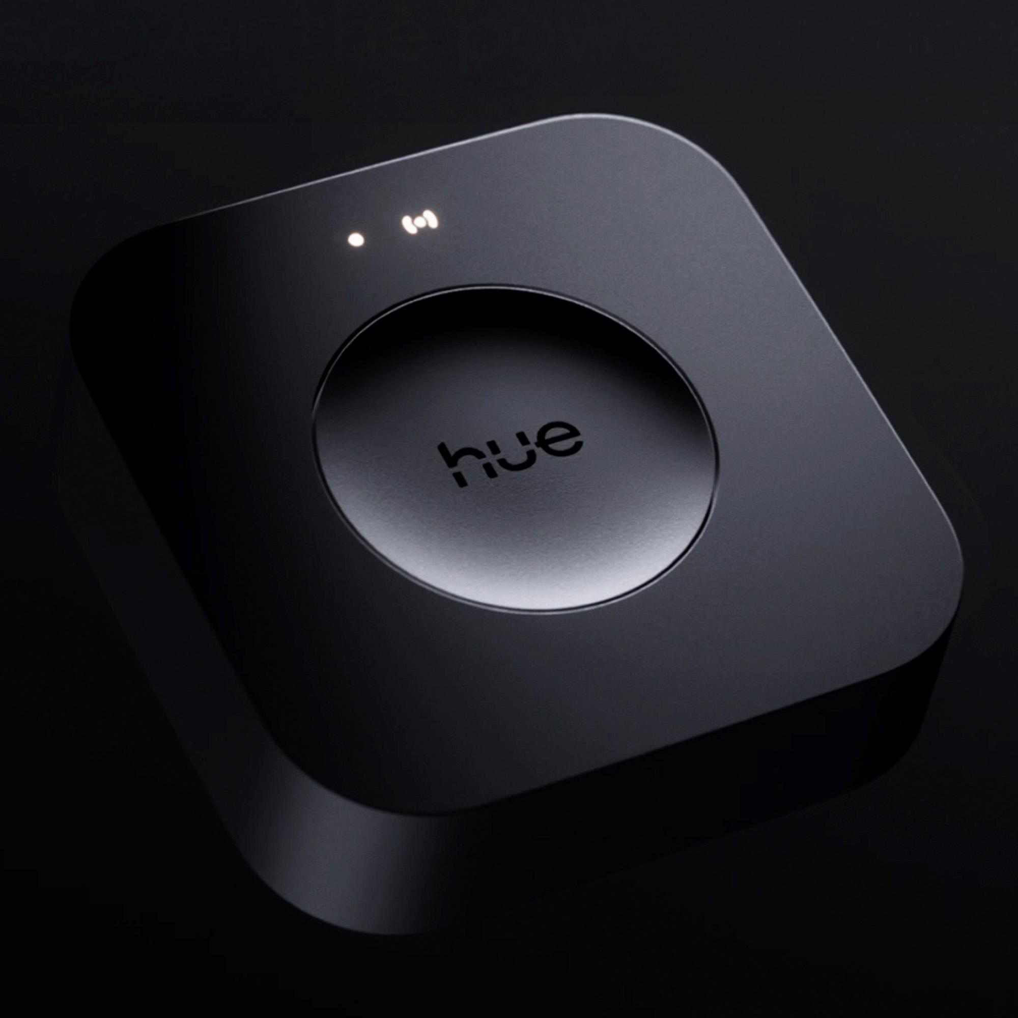 Schwarzes, quadratisches Gerät mit abgerundeten Kanten. Ein Kreis in der Mitte hat das Wort 'hue'. Zwei kleine Lichter sind oben.