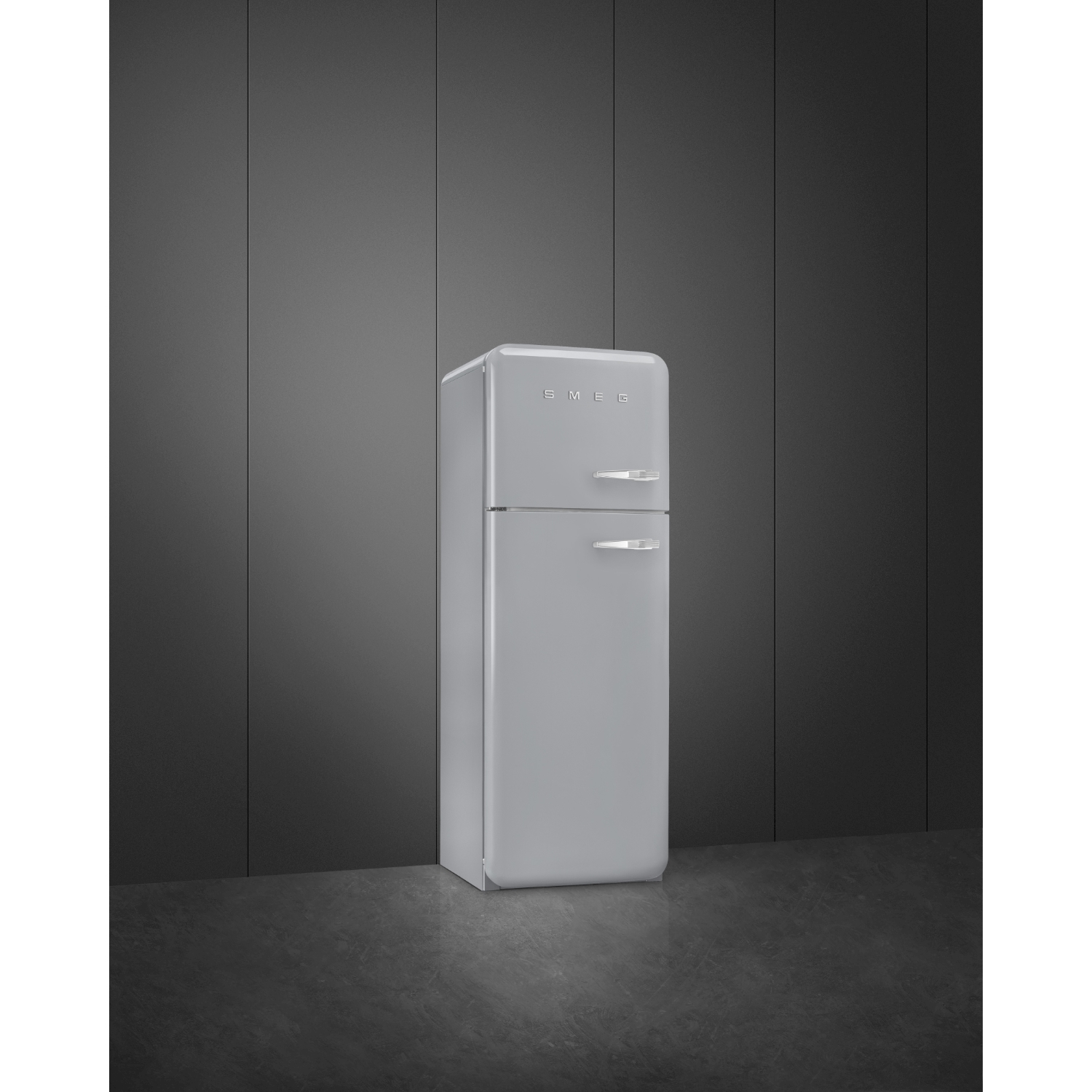 Un frigorifero Smeg grigio chiaro si trova contro un muro grigio scuro. Il pavimento è in pietra grigio scuro.