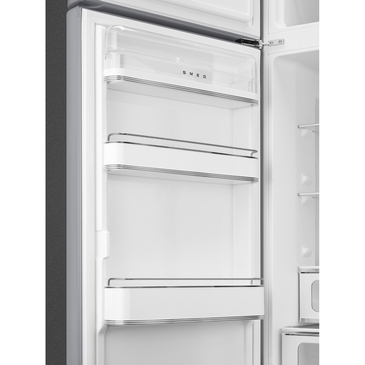 Un frigorifero SMEG bianco aperto e vuoto. Ha ripiani, un ripiano superiore trasparente e dettagli in acciaio inossidabile. La porta è socchiusa.