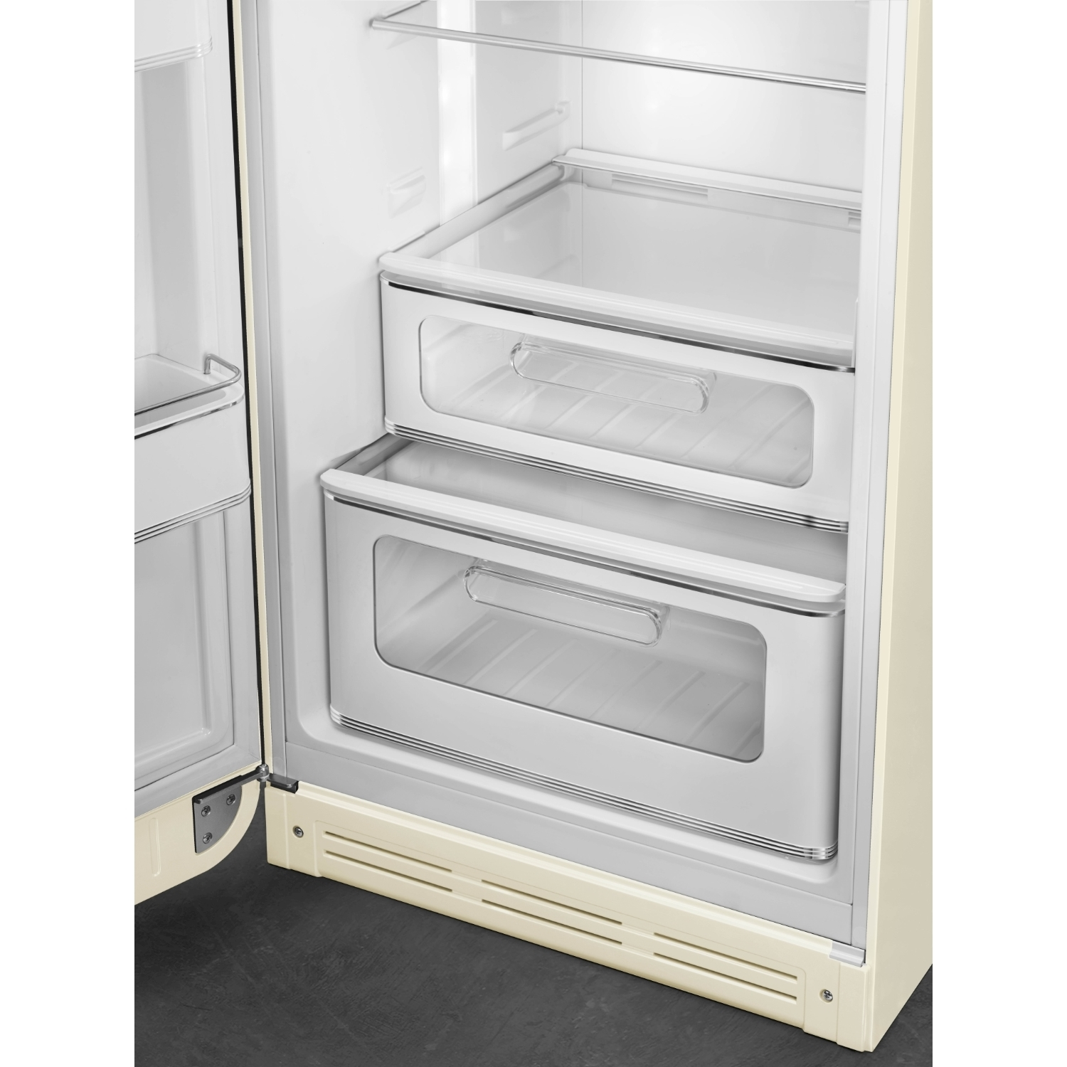 Frigorifero aperto con due cassetti. Esterno color crema, interno bianco. Cassetti trasparenti con maniglie argentate. Pavimento grigio scuro.