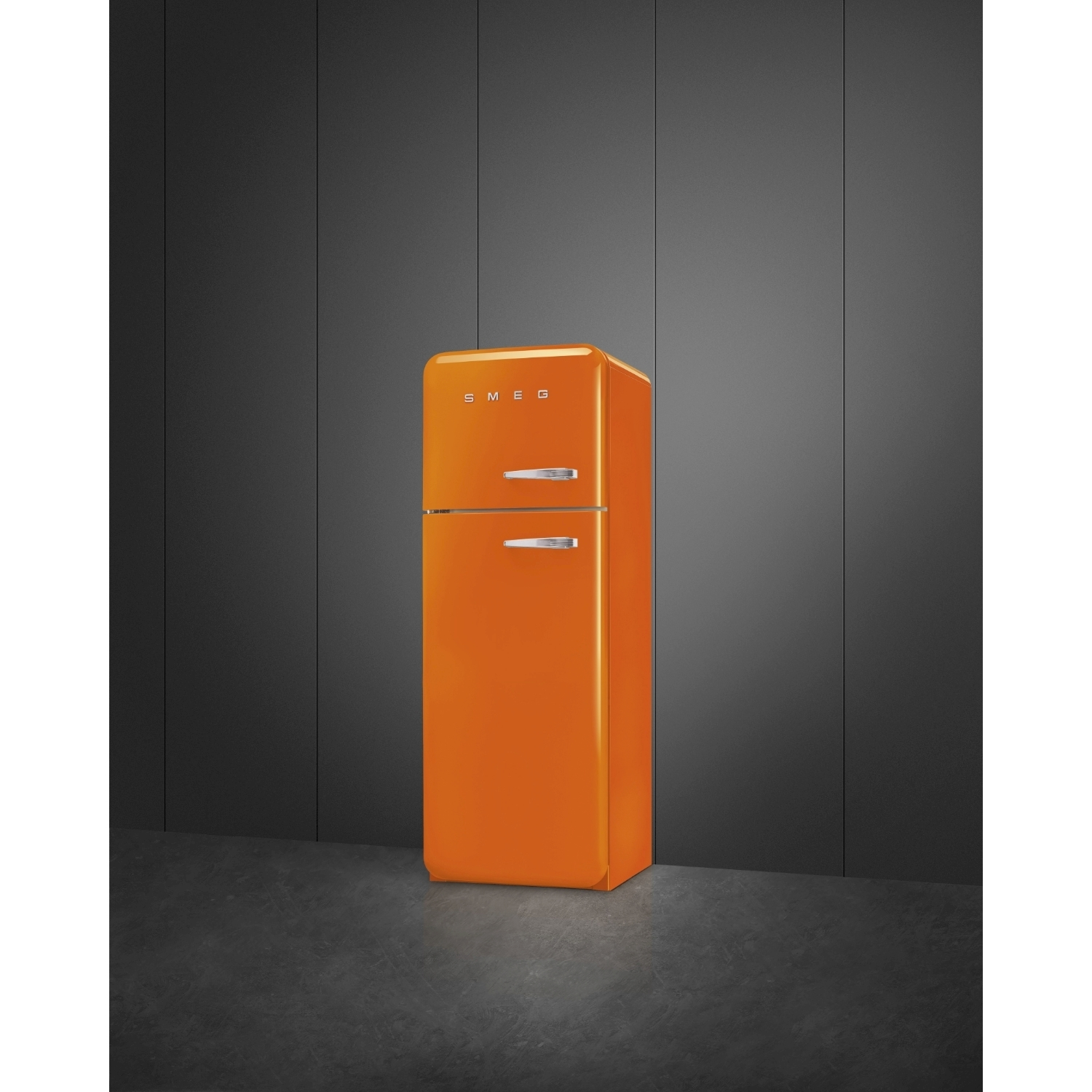 Un frigorifero Smeg retrò arancione si trova contro un muro grigio scuro. Anche il pavimento è grigio scuro. Il frigorifero ha maniglie argentate.