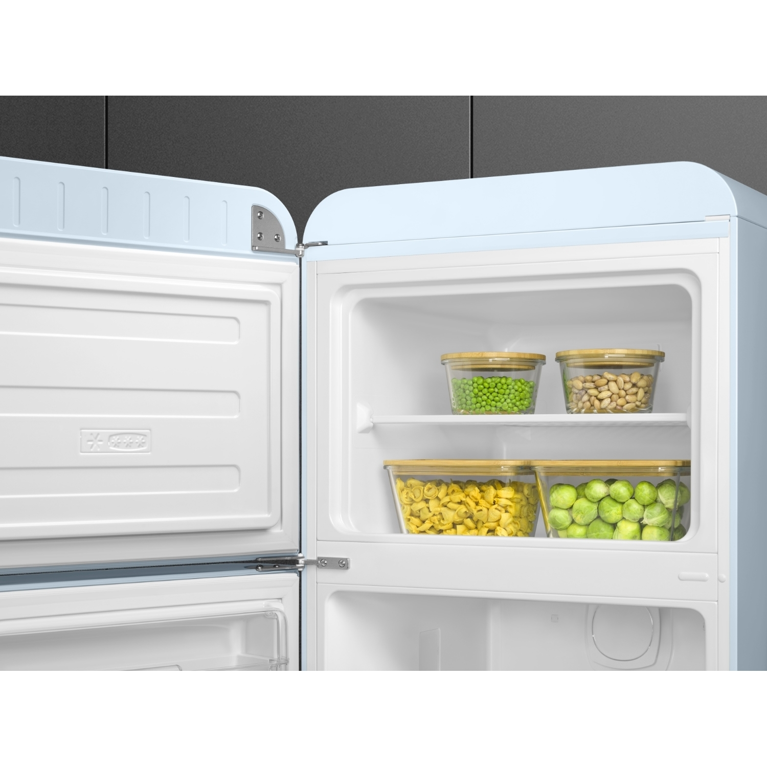 Frigorifero azzurro aperto con contenitori di cibo all'interno. Contiene piselli, fagioli, pasta e cavoletti di Bruxelles.