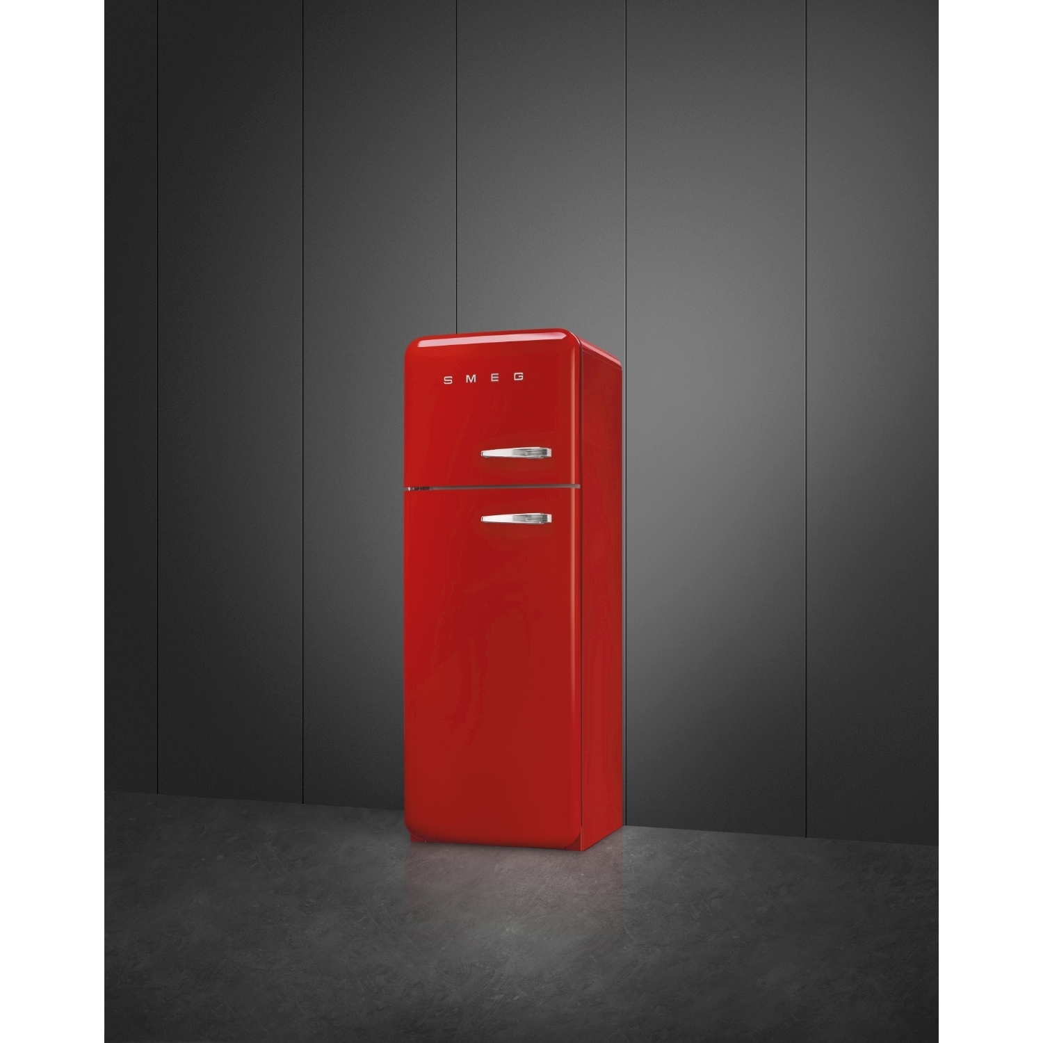 Un frigorifero Smeg rosso si trova contro un muro grigio scuro. Il frigorifero ha maniglie argentate e il logo Smeg in alto.