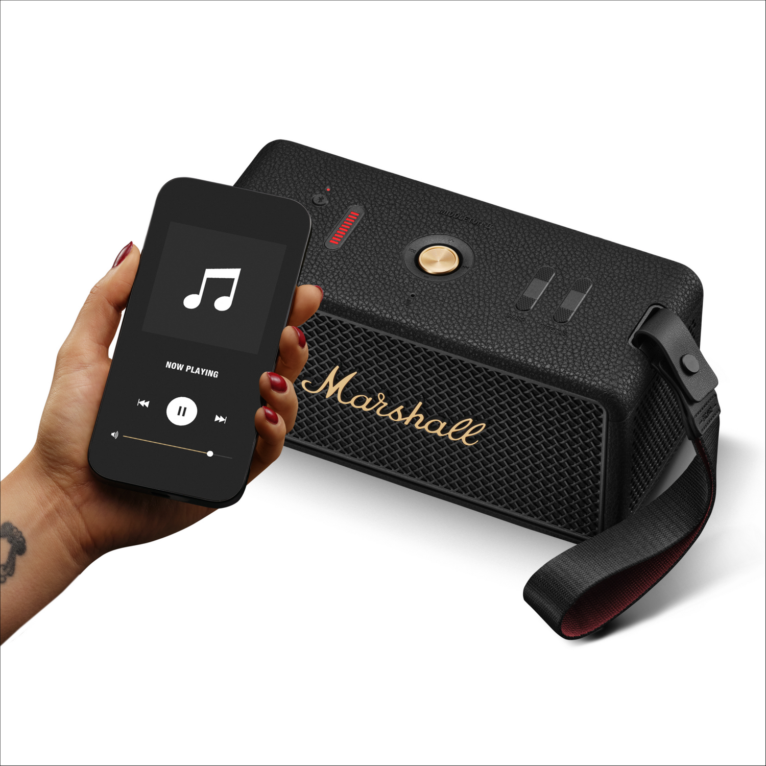 Una mano sostiene un teléfono que reproduce música. Un altavoz Marshall negro está en el lado derecho.