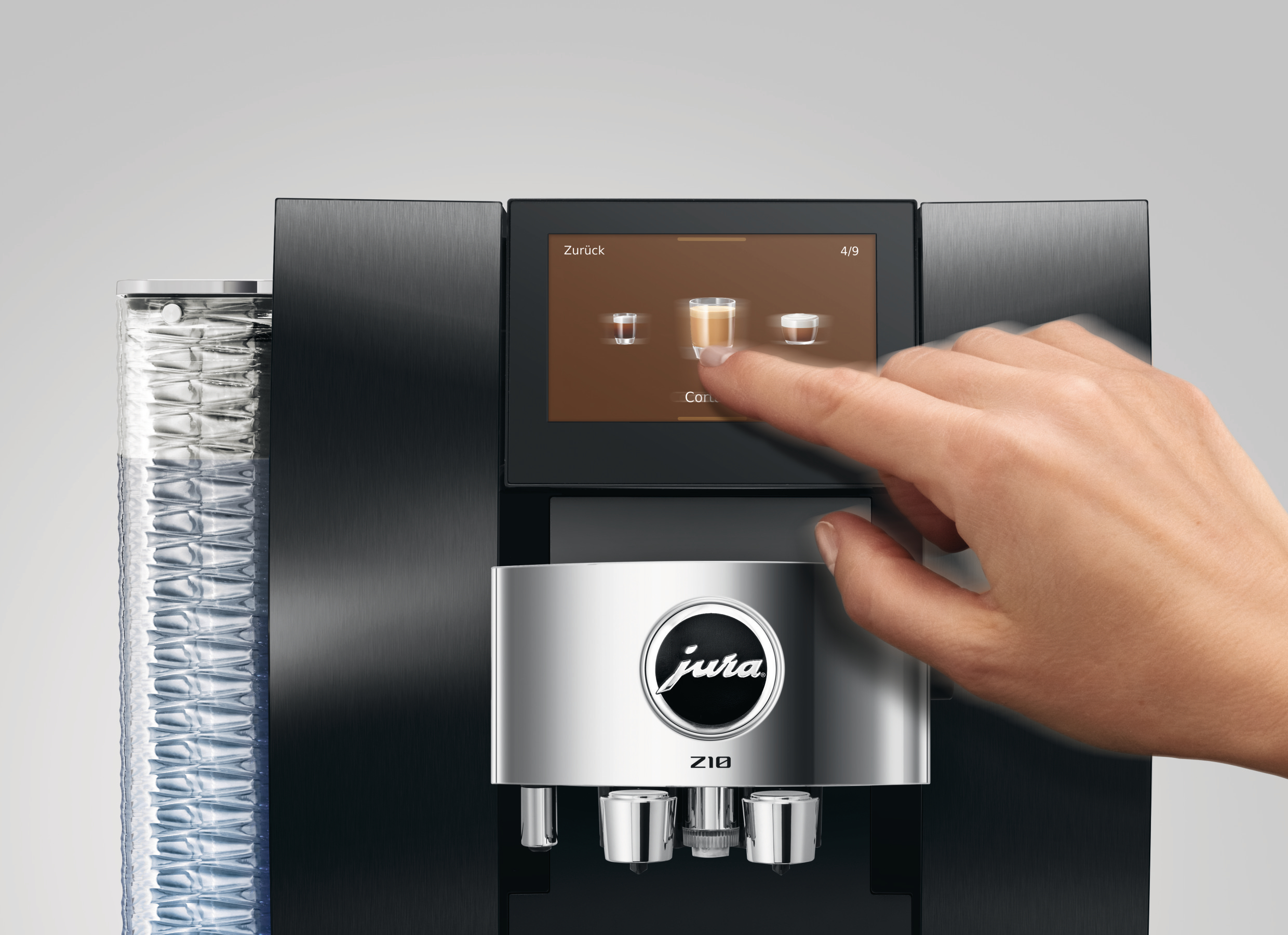 Eine Hand berührt den Bildschirm einer Kaffeemaschine, auf dem Kaffeeoptionen angezeigt werden. Links ist ein Glastank.