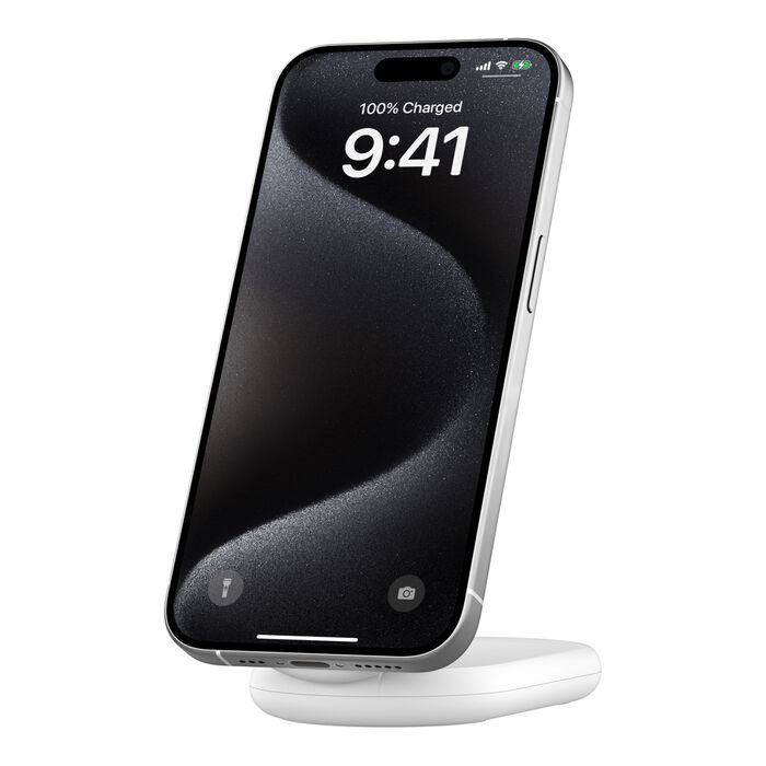 Un iPhone negro que muestra 9:41, 100% cargado, en un soporte de carga blanco. Lados plateados y una pantalla negra son visibles.
