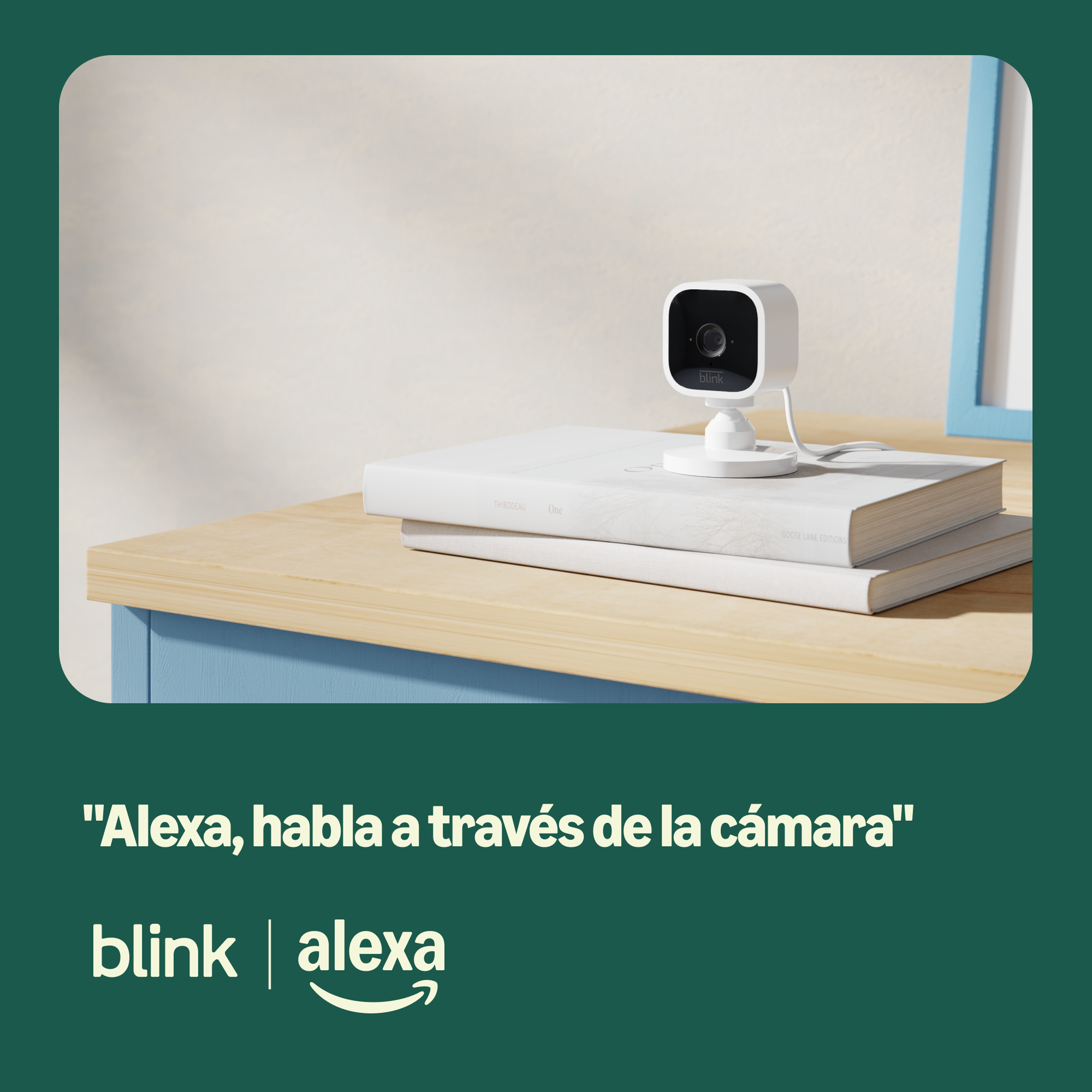 Una cámara de seguridad Blink blanca sobre libros. La escena incluye una mesa de madera, un marco azul y los logotipos de Alexa y Blink.