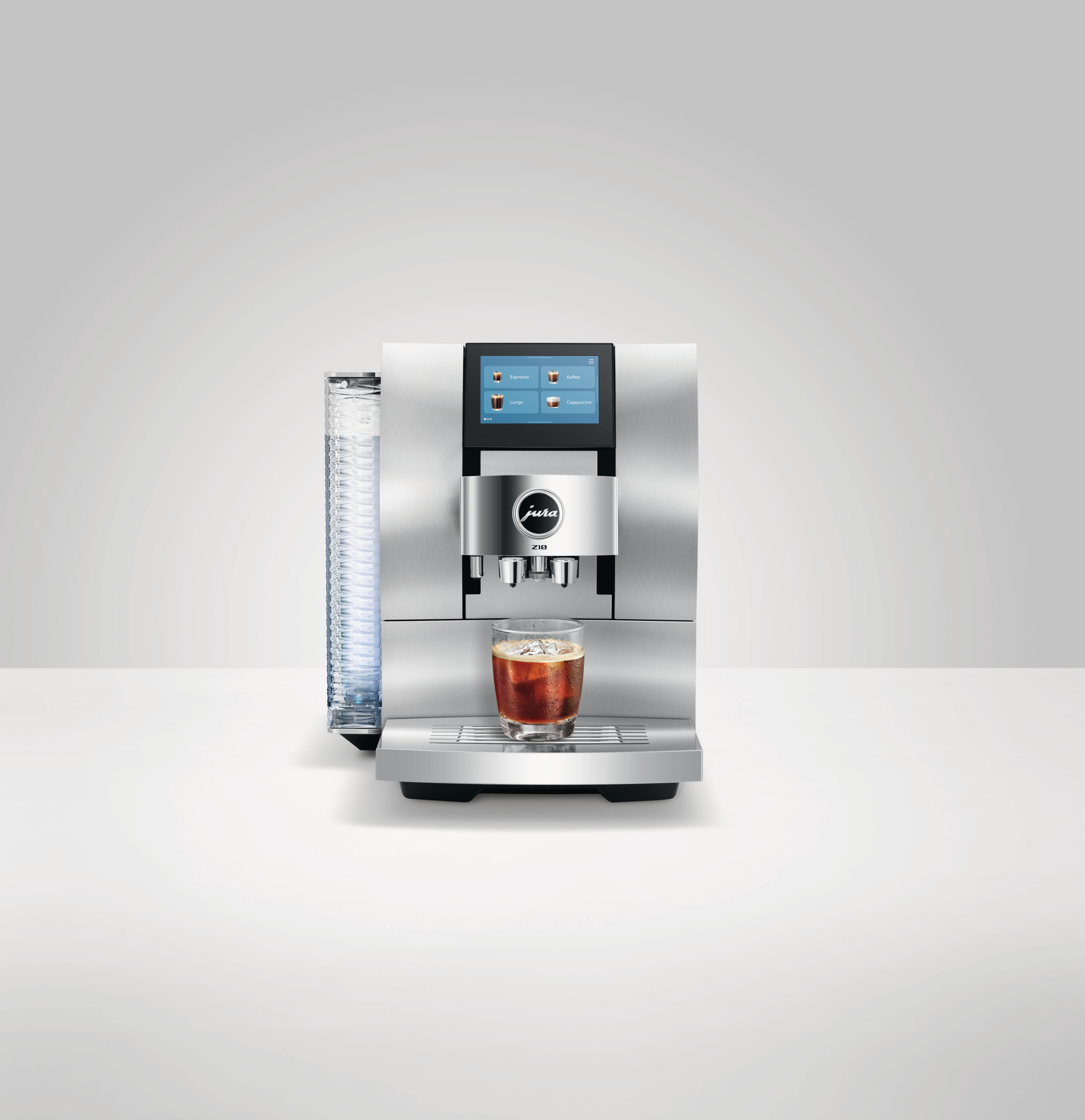 Eine silberne Jura-Kaffeemaschine mit einem Glas Kaffee. Links ein Wasserbehälter. Der Hintergrund ist weiß.