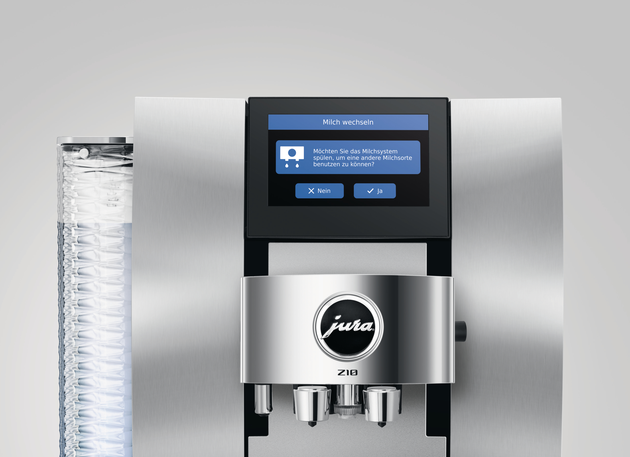 Nahaufnahme einer Jura Kaffeemaschine mit Bildschirm, der zur Milchsystemreinigung auffordert.